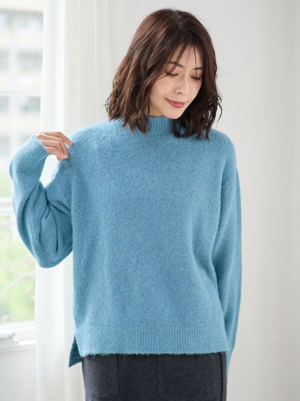 ブルー系のニット/セーターを着用したレディースの冬コーディネートの2枚目の写真