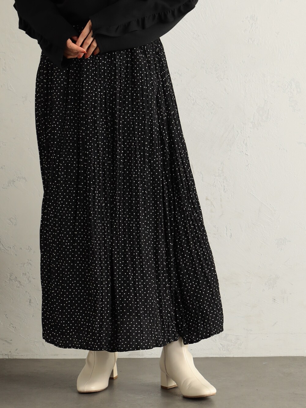 ベージュ系のブーツ、ブラック系のTシャツ/カットソー、ベージュ系のスカートを着用したレディースの冬コーディネートの2枚目の写真