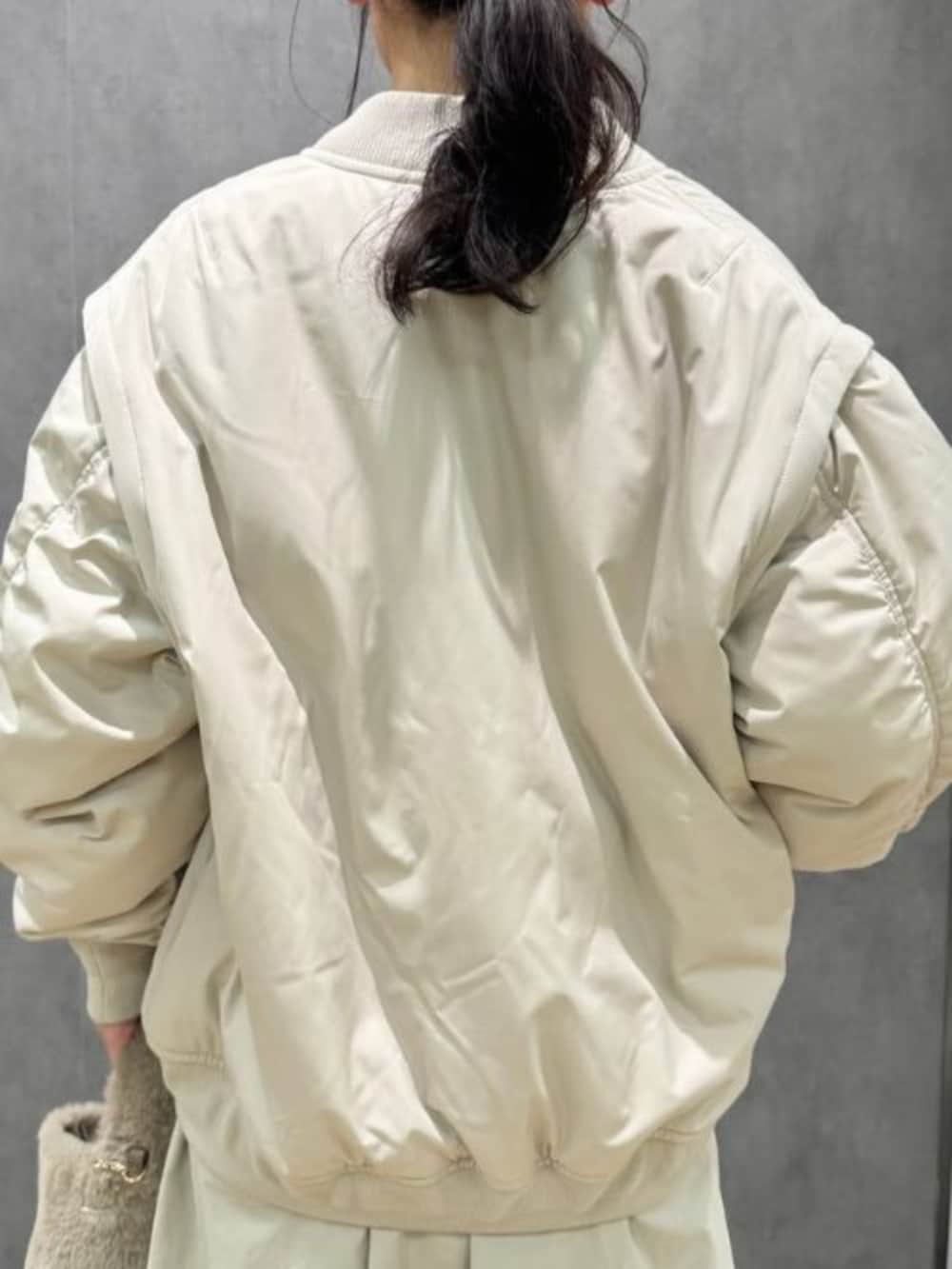 ブルー系のニット/セーター、ベージュ系のスカート、ベージュ系のMA-1を着用したレディースの冬コーディネートの3枚目の写真