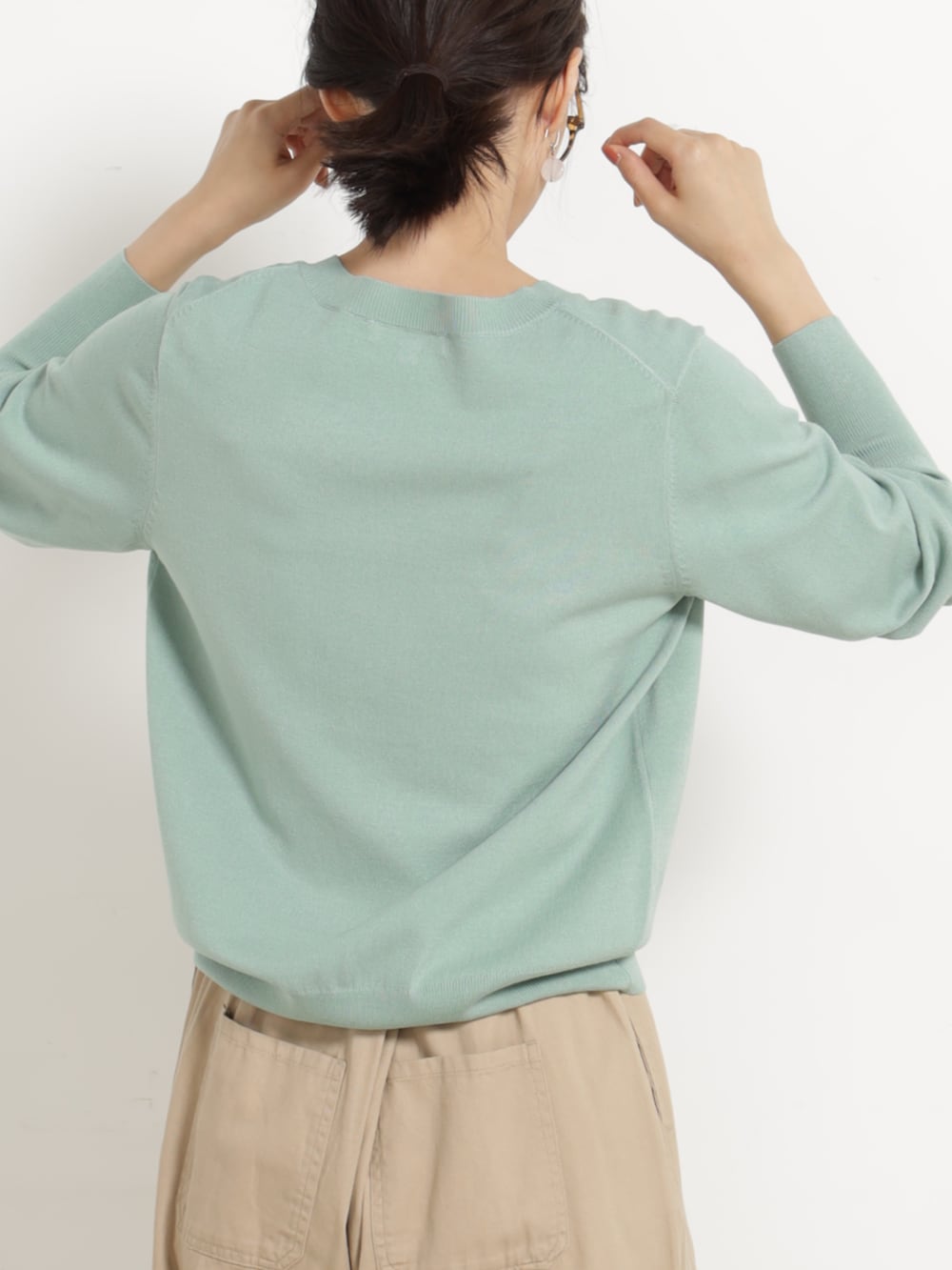 ベージュ系のチノパンツ、グリーン系のニット/セーターを着用したレディースの秋コーディネートの3枚目の写真