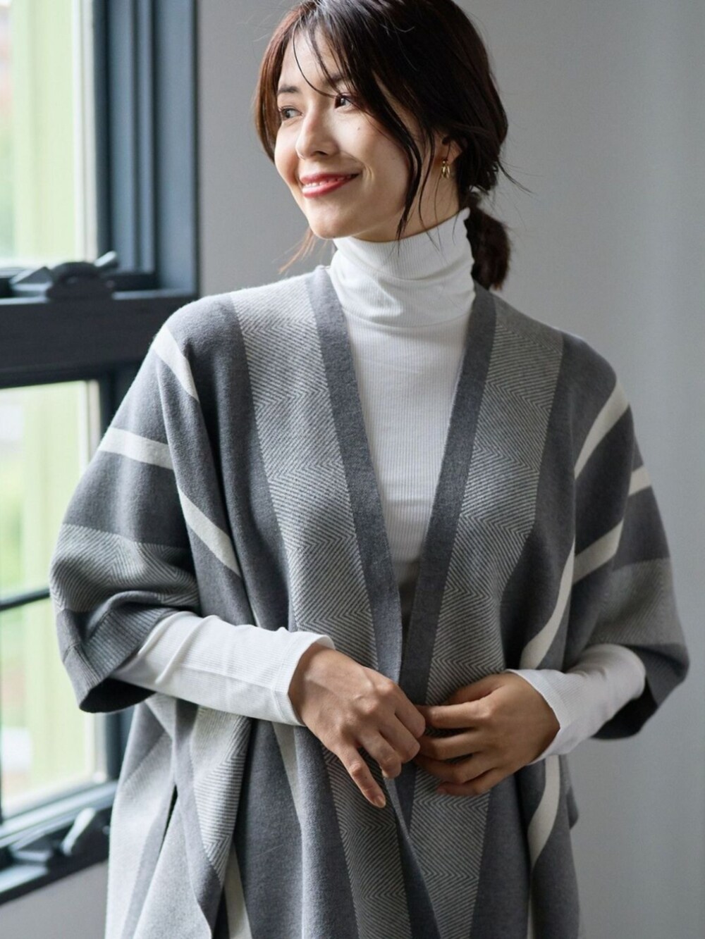 グレー系のポンチョを着用したレディースの冬コーディネートの2枚目の写真