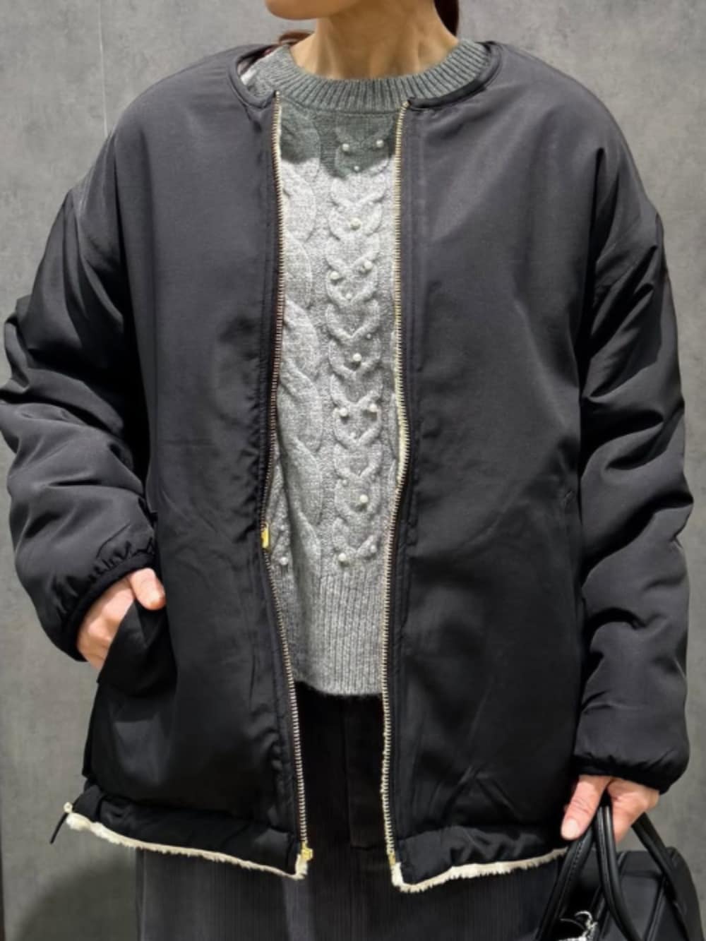 ブラック系のブルゾン、グレー系のニット/セーター、グレー系のスカートを着用したレディースの冬コーディネートの3枚目の写真