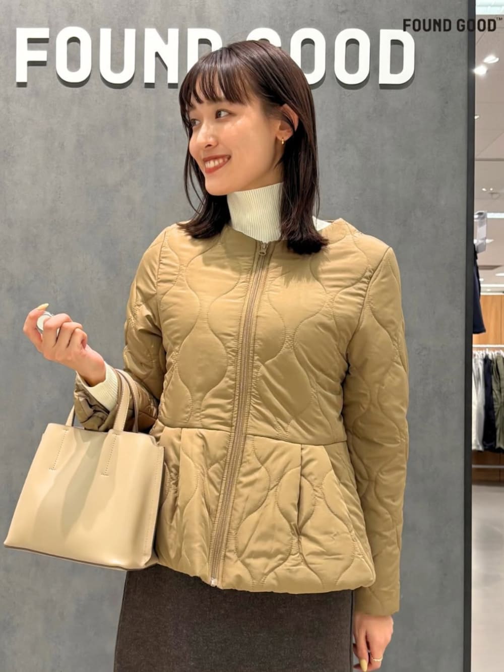 ベージュ系のハンドバッグ、ブラウン系のブルゾン、グリーン系のスカートを着用したレディースの冬コーディネートの2枚目の写真