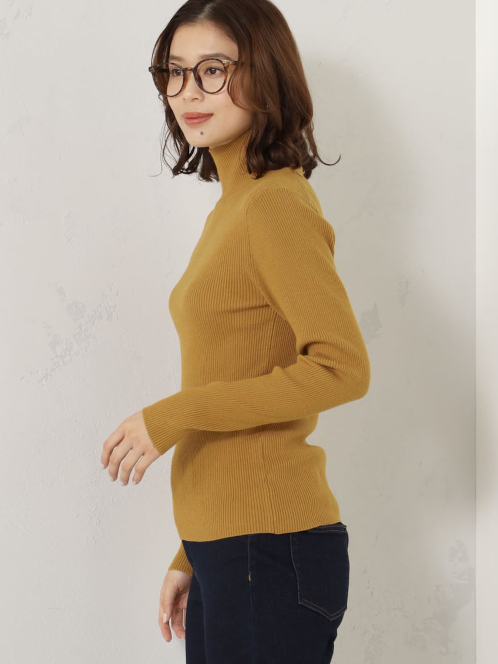 イエロー系のニット/セーター、ブルー系のネックウォーマー/スヌード、ベージュ系の手袋を着用したレディースの冬コーディネートの3枚目の写真