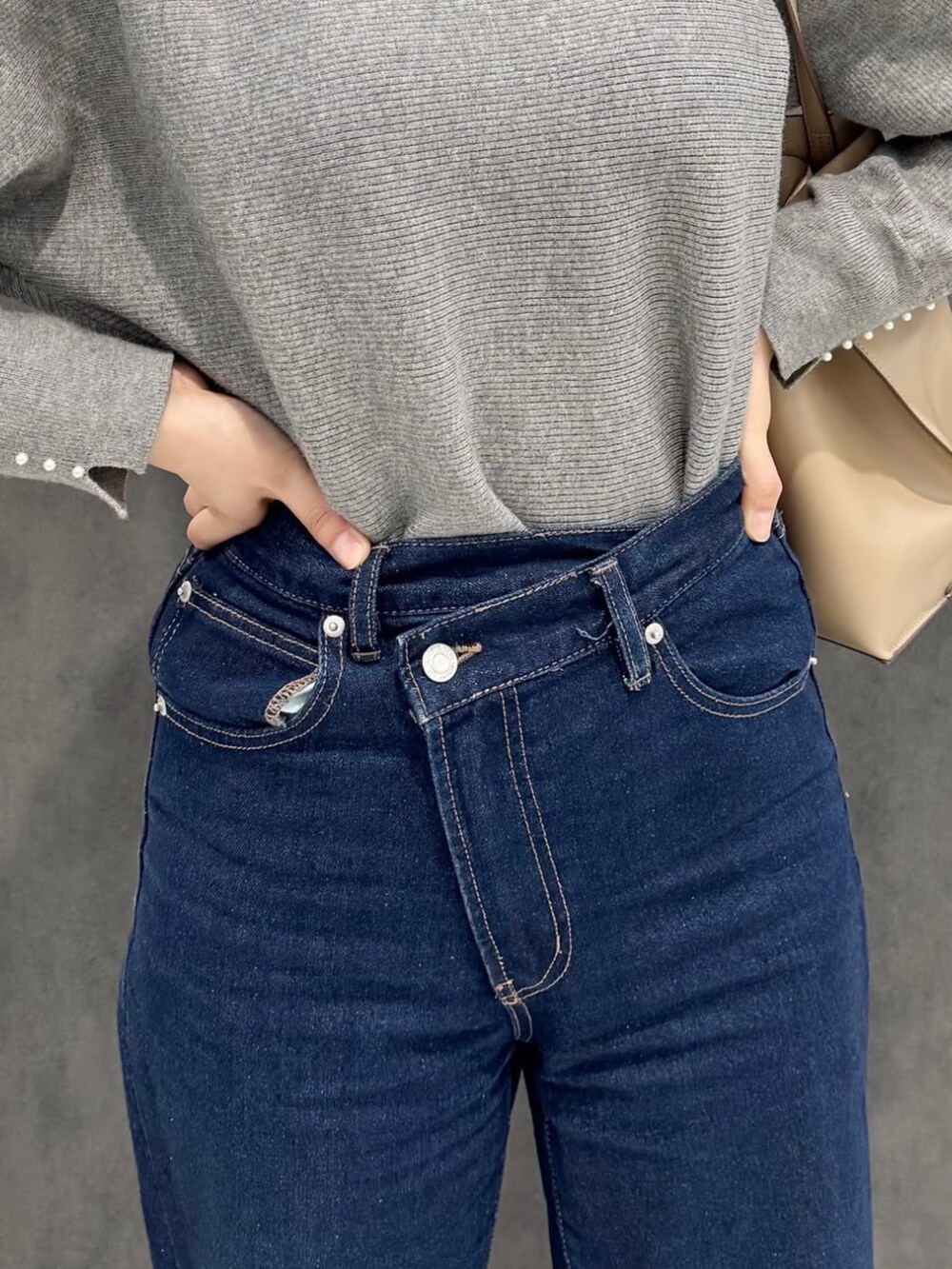 ブルー系のデニムパンツ、グレー系のニット/セーター、ベージュ系のパンプスを着用したレディースの冬コーディネートの3枚目の写真