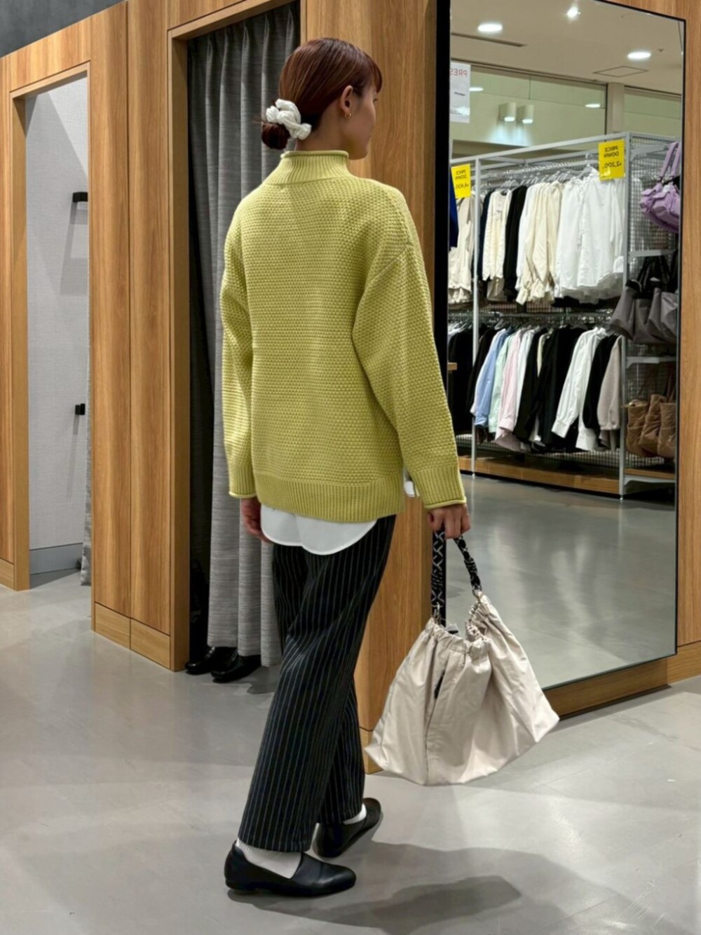 イエロー系のニット/セーター、グレー系のその他パンツを着用したレディースの冬コーディネートの2枚目の写真