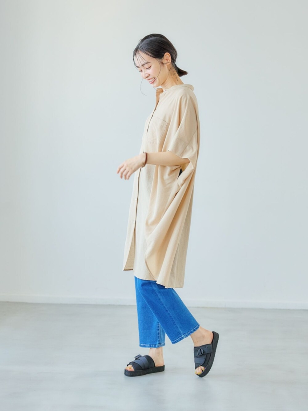 ベージュ系のチュニックを着用したレディースの夏コーディネートの2枚目の写真