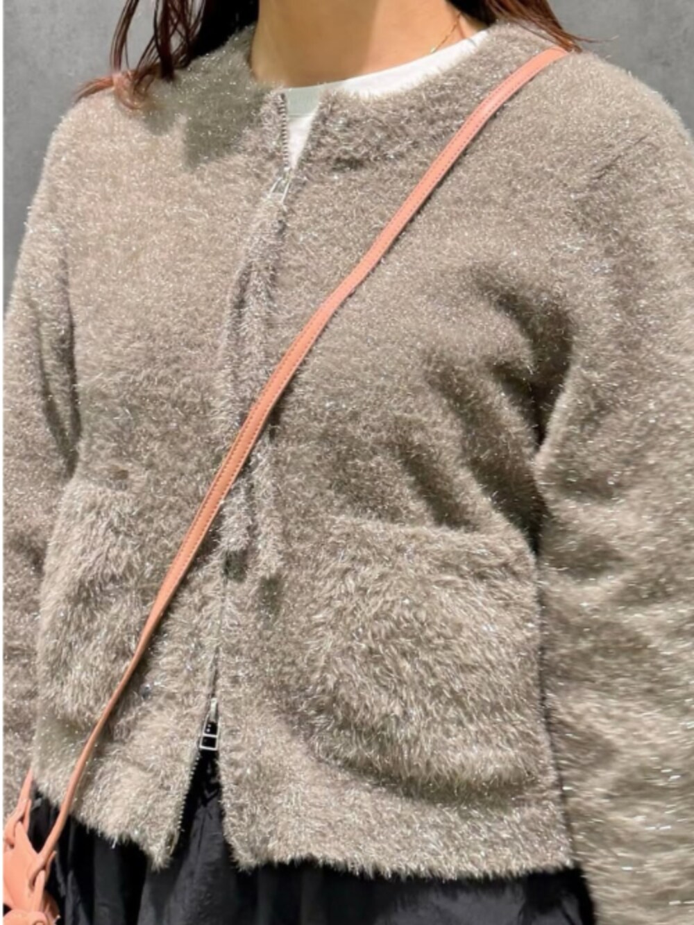 ピンク系のショルダーバッグ、ブラウン系のカーディガン/ボレロ、ブラック系のスカートを着用したレディースの冬コーディネートの3枚目の写真