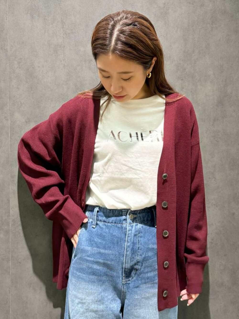 レッド系のカーディガン/ボレロ、ブルー系のデニムパンツ、ベージュ系のTシャツ/カットソーを着用したレディースの秋コーディネートの2枚目の写真