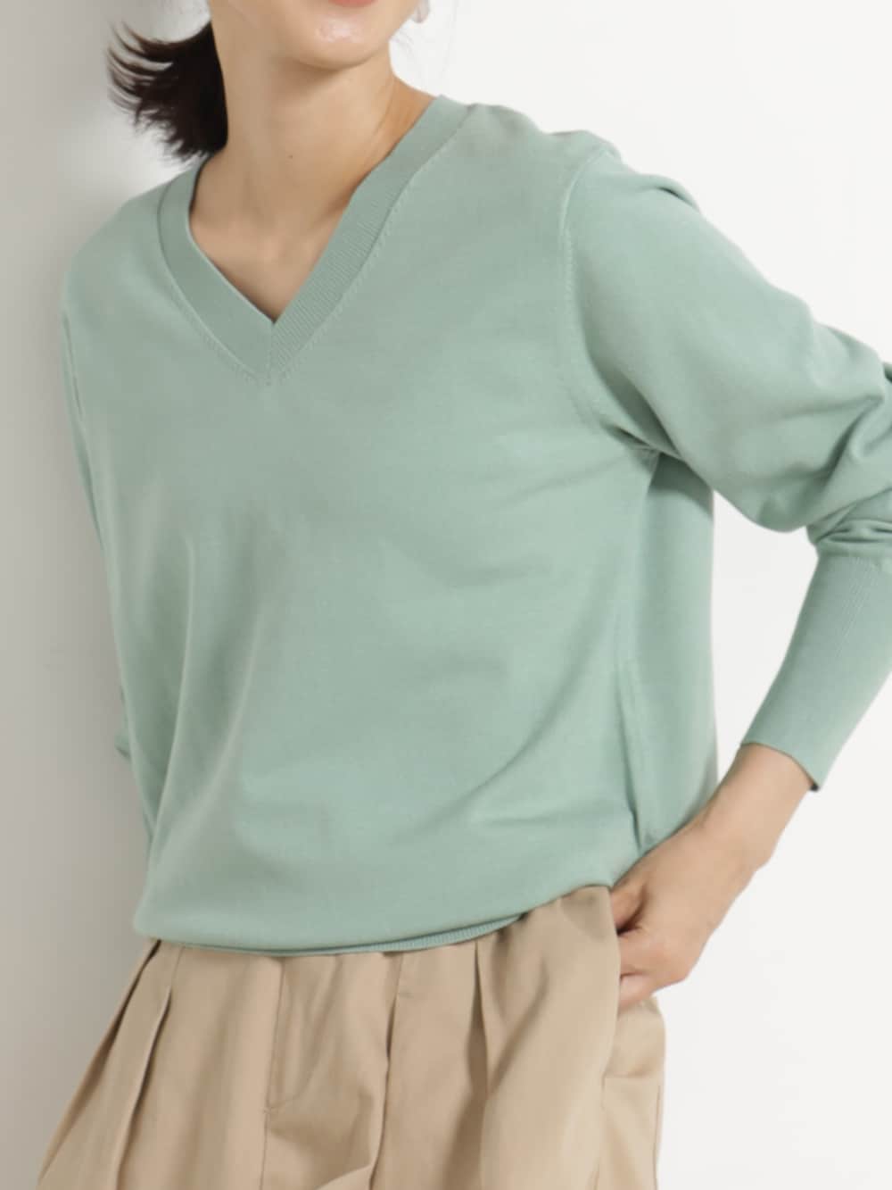 ベージュ系のチノパンツ、グリーン系のニット/セーターを着用したレディースの秋コーディネートの2枚目の写真