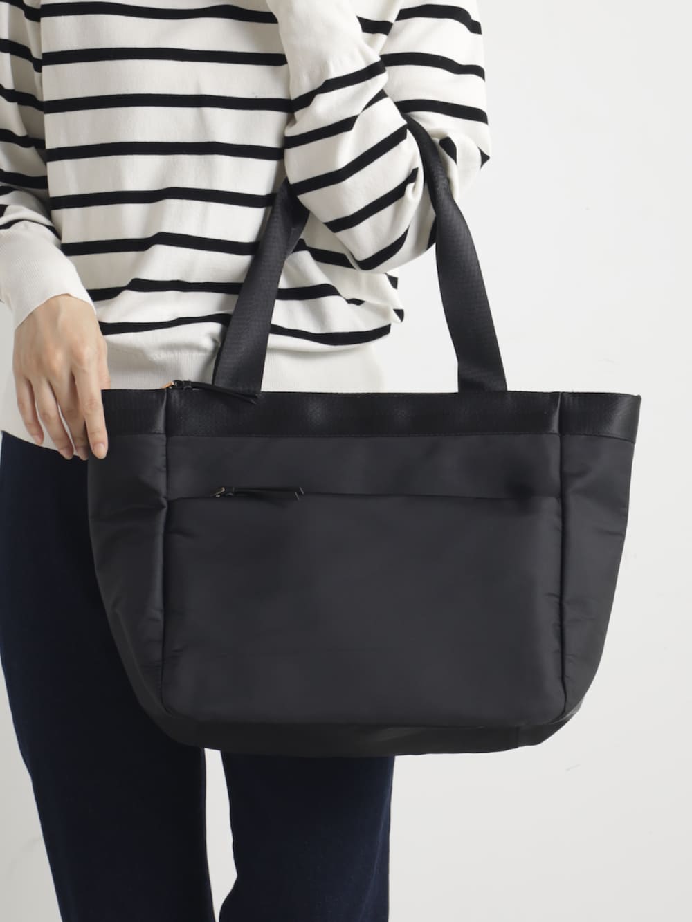 グレー系のニット/セーター、ブラック系のトートバッグを着用したレディースの春コーディネートの2枚目の写真