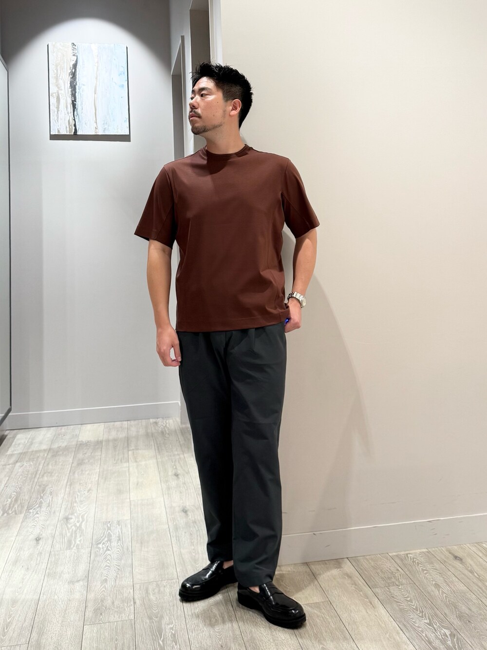 ブラウン系のTシャツ/カットソー、グレー系のスラックスを着用したメンズの夏コーディネートの4枚目の写真