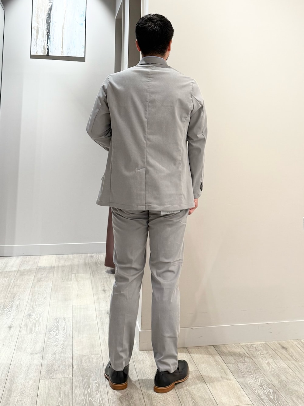 グレー系のテーラードジャケット、ブルー系のTシャツ/カットソー、グレー系のスラックスを着用したメンズの夏コーディネートの3枚目の写真