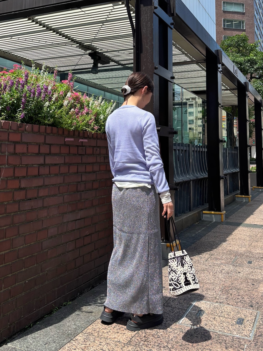 パープル系のニット/セーター、ホワイト系のTシャツ/カットソー、グレー系のスカートを着用したレディースの夏コーディネートの3枚目の写真