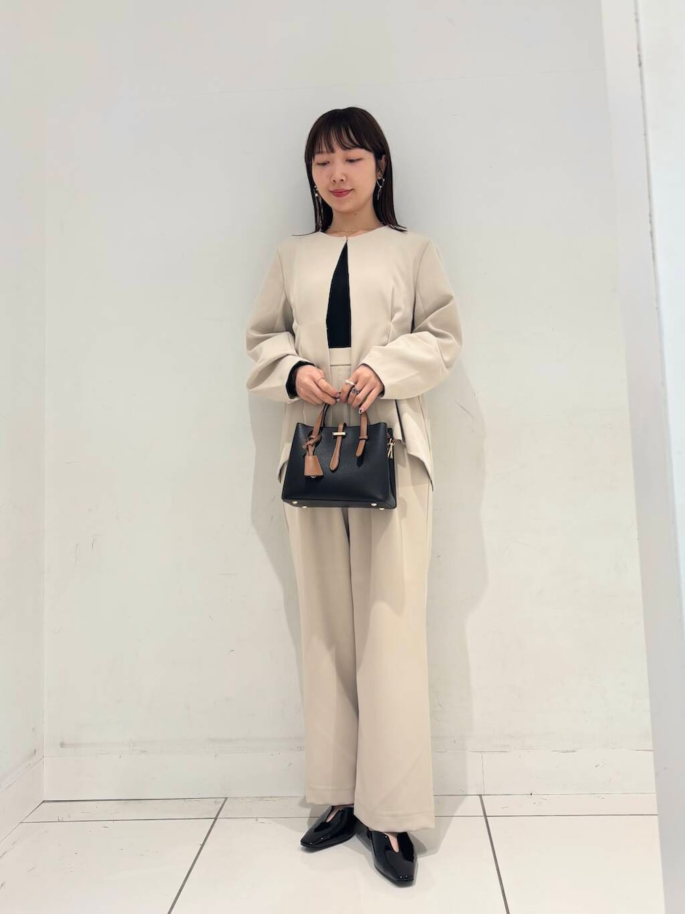 ブラック系のハンドバッグ、ブラック系のTシャツ/カットソー、ブラック系のパンプスを着用したレディースの冬コーディネートの2枚目の写真