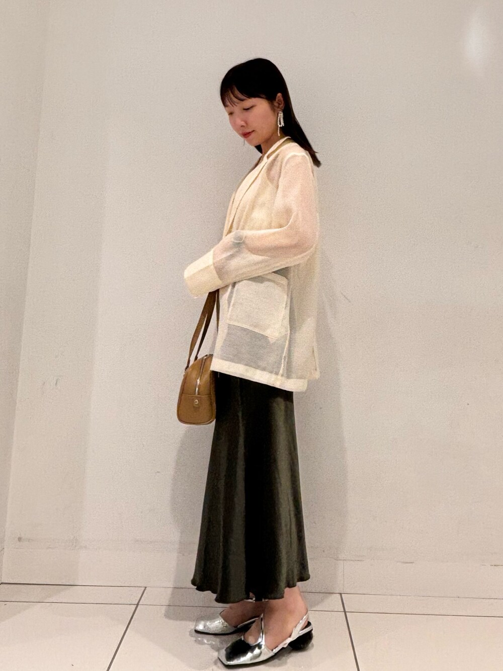 ブラウン系のテーラードジャケット、グリーン系のボストンバッグ、グリーン系のスカートを着用したレディースの秋コーディネートの2枚目の写真