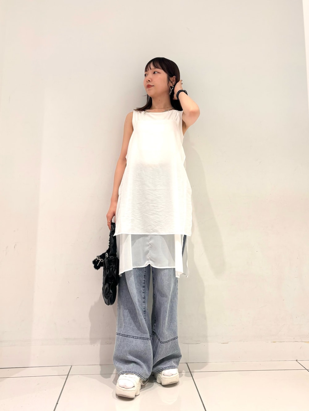 ホワイト系のワンピース、ブラック系のハンドバッグ、ブルー系のデニムパンツを着用したレディースの夏コーディネートの4枚目の写真