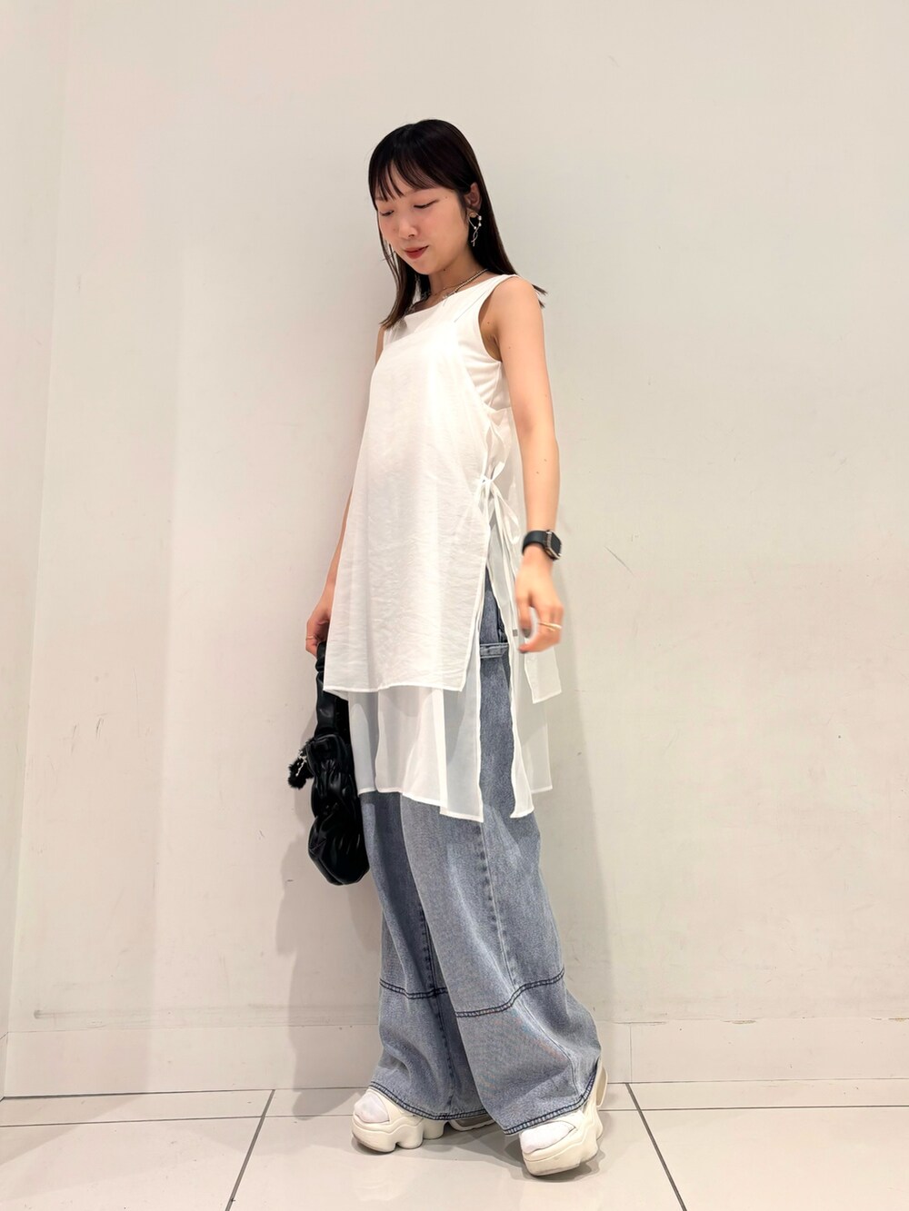 ホワイト系のワンピース、ブラック系のハンドバッグ、ブルー系のデニムパンツを着用したレディースの夏コーディネートの3枚目の写真