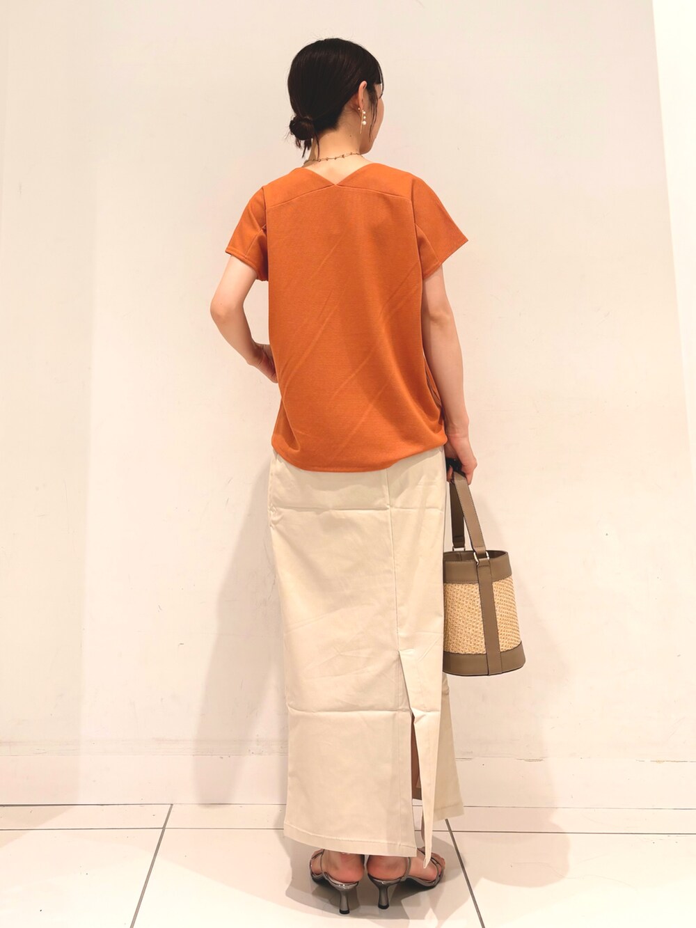 オレンジ系のTシャツ/カットソー、グレー系のショルダーバッグ、ベージュ系のスカートを着用したレディースの夏コーディネートの4枚目の写真