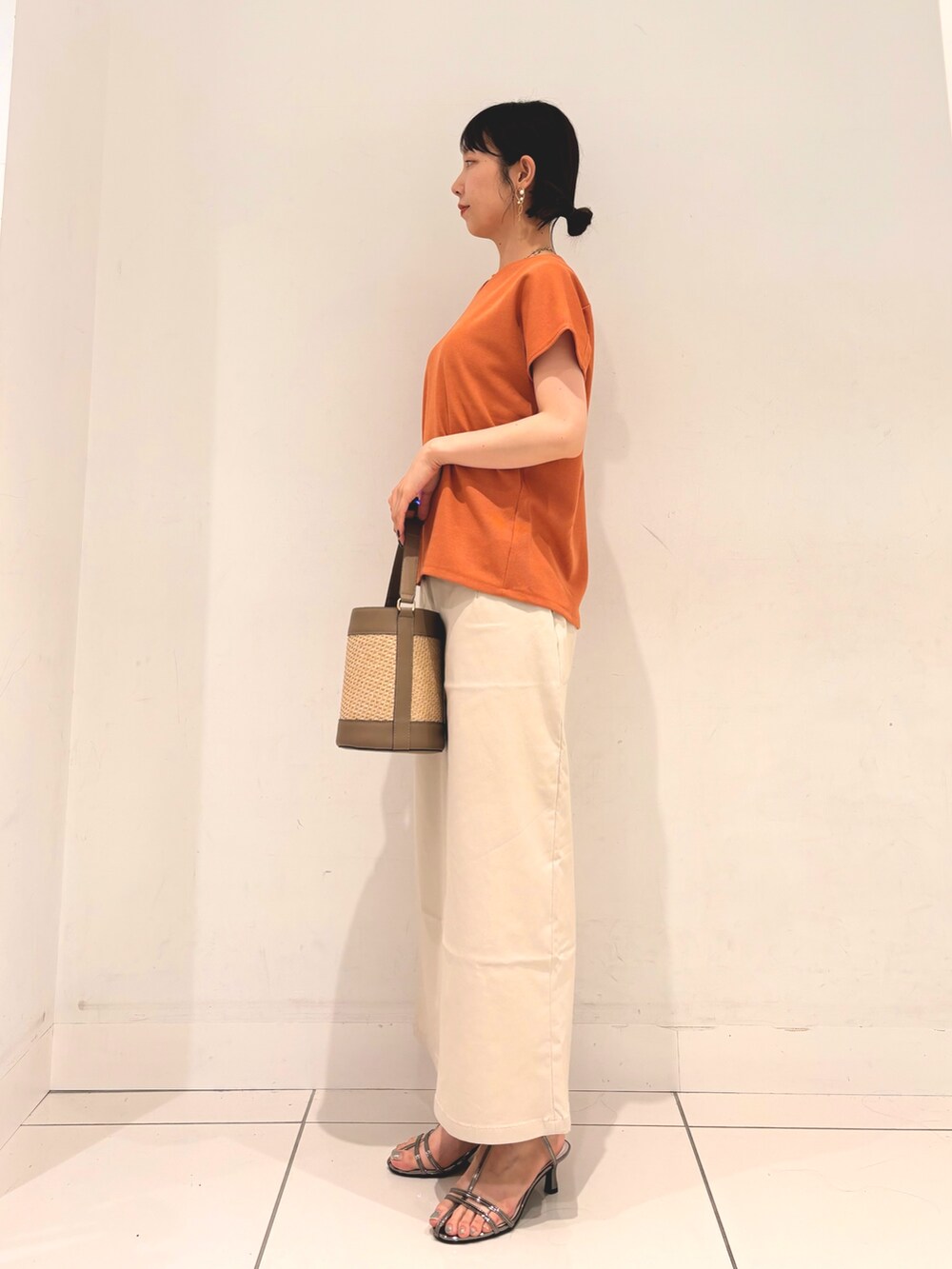 オレンジ系のTシャツ/カットソー、グレー系のショルダーバッグ、ベージュ系のスカートを着用したレディースの夏コーディネートの2枚目の写真