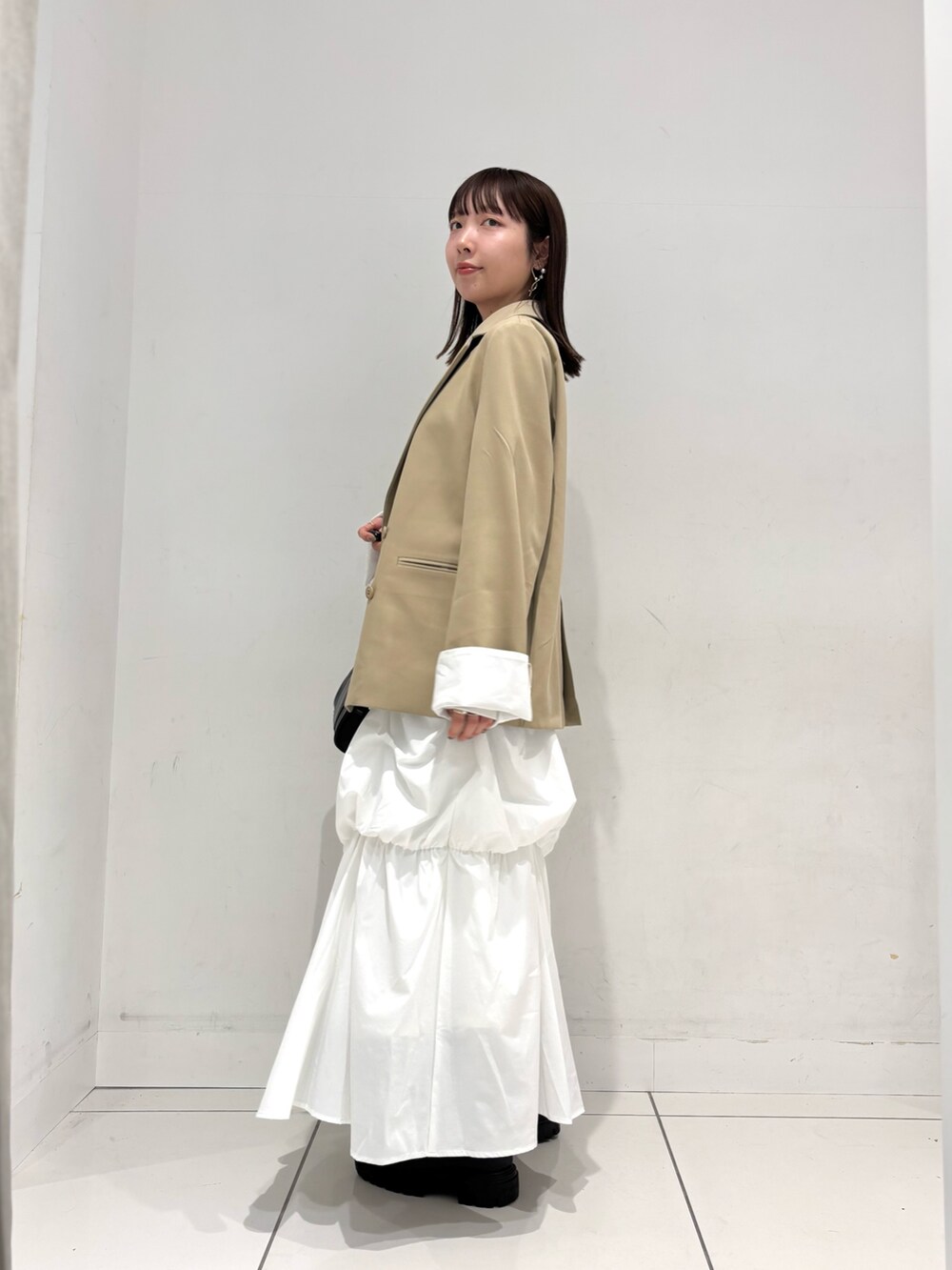 ベージュ系のテーラードジャケット、ホワイト系のTシャツ/カットソー、グリーン系のスカートを着用したレディースの冬コーディネートの3枚目の写真