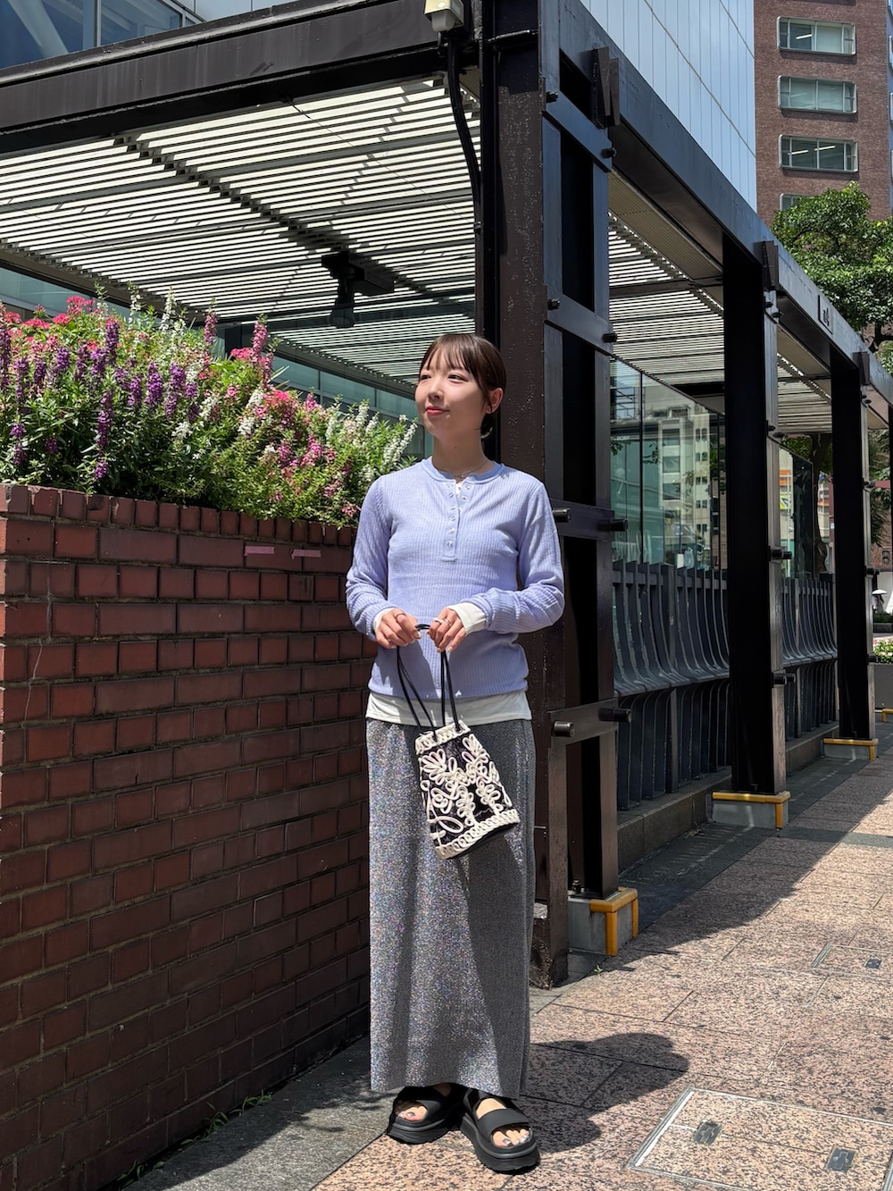 パープル系のニット/セーター、ホワイト系のTシャツ/カットソー、グレー系のスカートを着用したレディースの夏コーディネートの2枚目の写真
