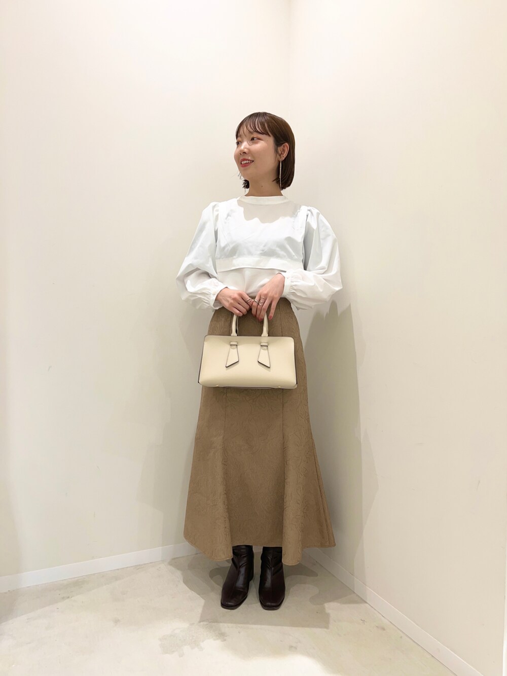 ベージュ系のスカート、ブラウン系のブーツ、ホワイト系のTシャツ/カットソーを着用したレディースの冬コーディネートの2枚目の写真