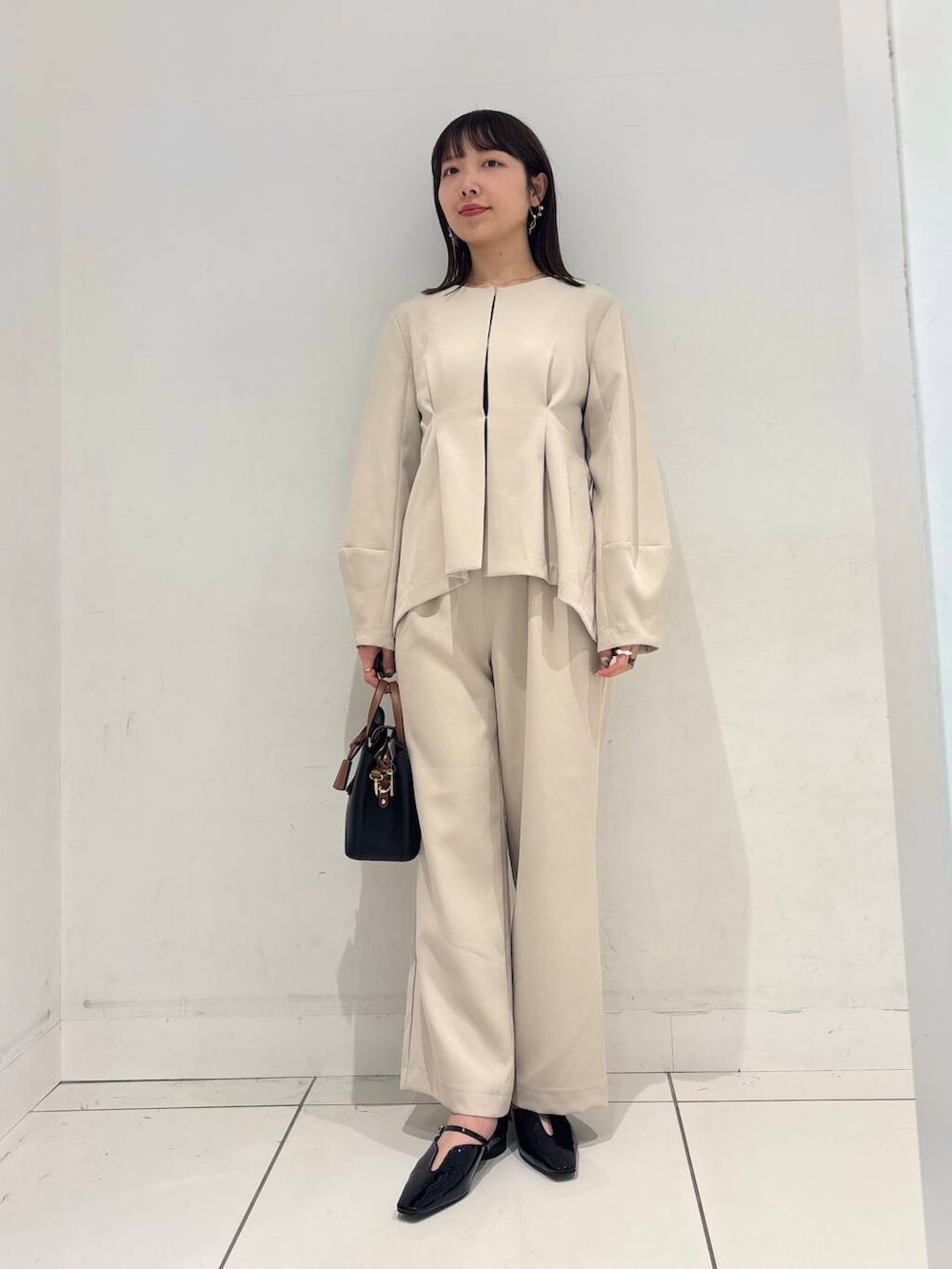 ブラック系のハンドバッグ、ブラック系のTシャツ/カットソー、ブラック系のパンプスを着用したレディースの冬コーディネートの5枚目の写真