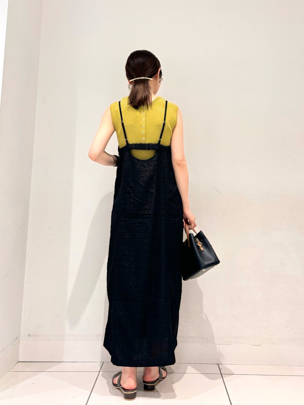 イエロー系のニット/セーター、ブラック系のワンピース、ブラック系のハンドバッグを着用したレディースの夏コーディネートの4枚目の写真