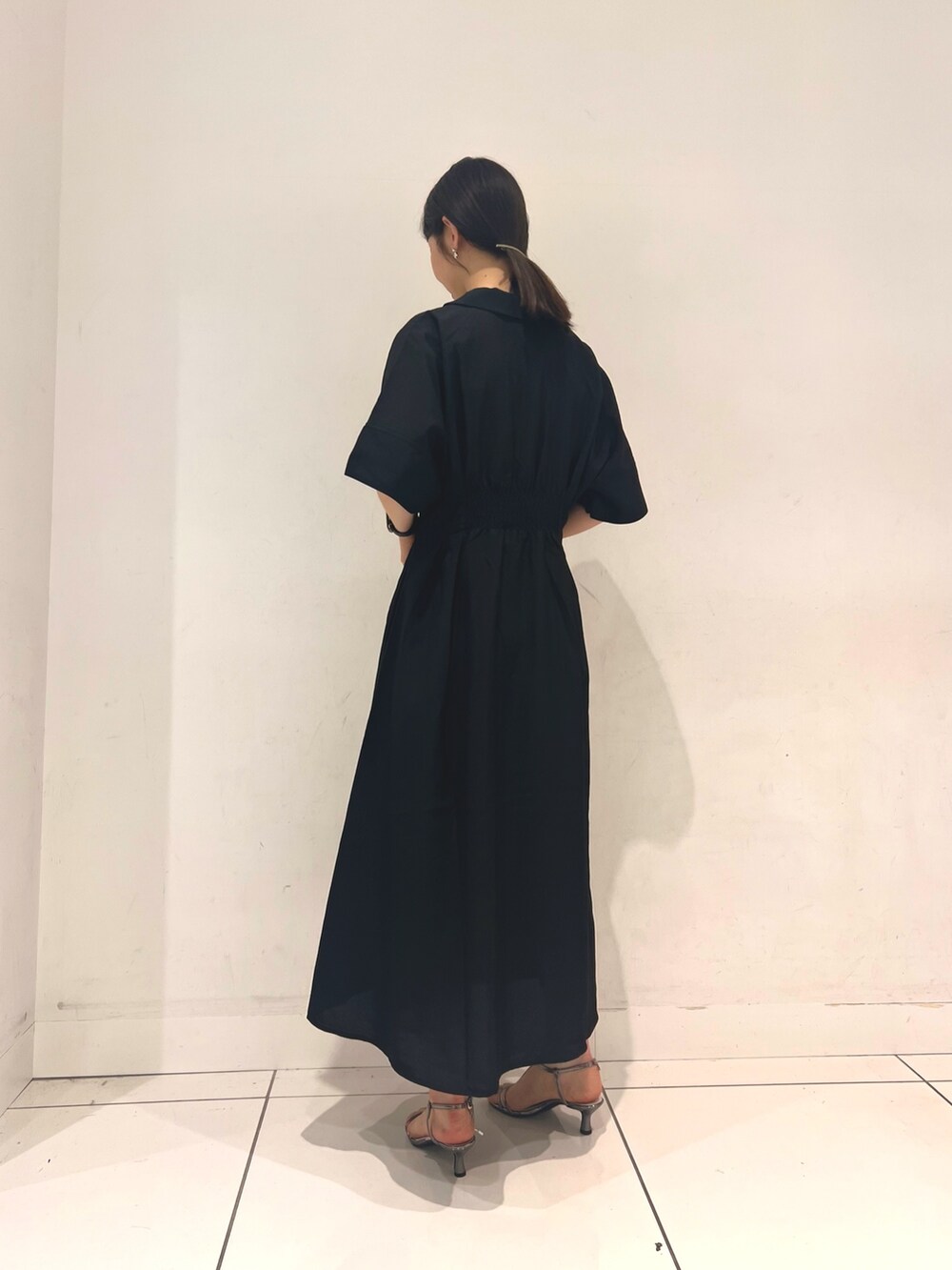 ブラック系のワンピース、ゴールド系のハンドバッグ、グレー系のサンダルを着用したレディースの夏コーディネートの2枚目の写真