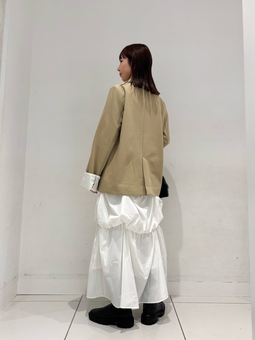 ベージュ系のテーラードジャケット、ホワイト系のTシャツ/カットソー、グリーン系のスカートを着用したレディースの冬コーディネートの4枚目の写真