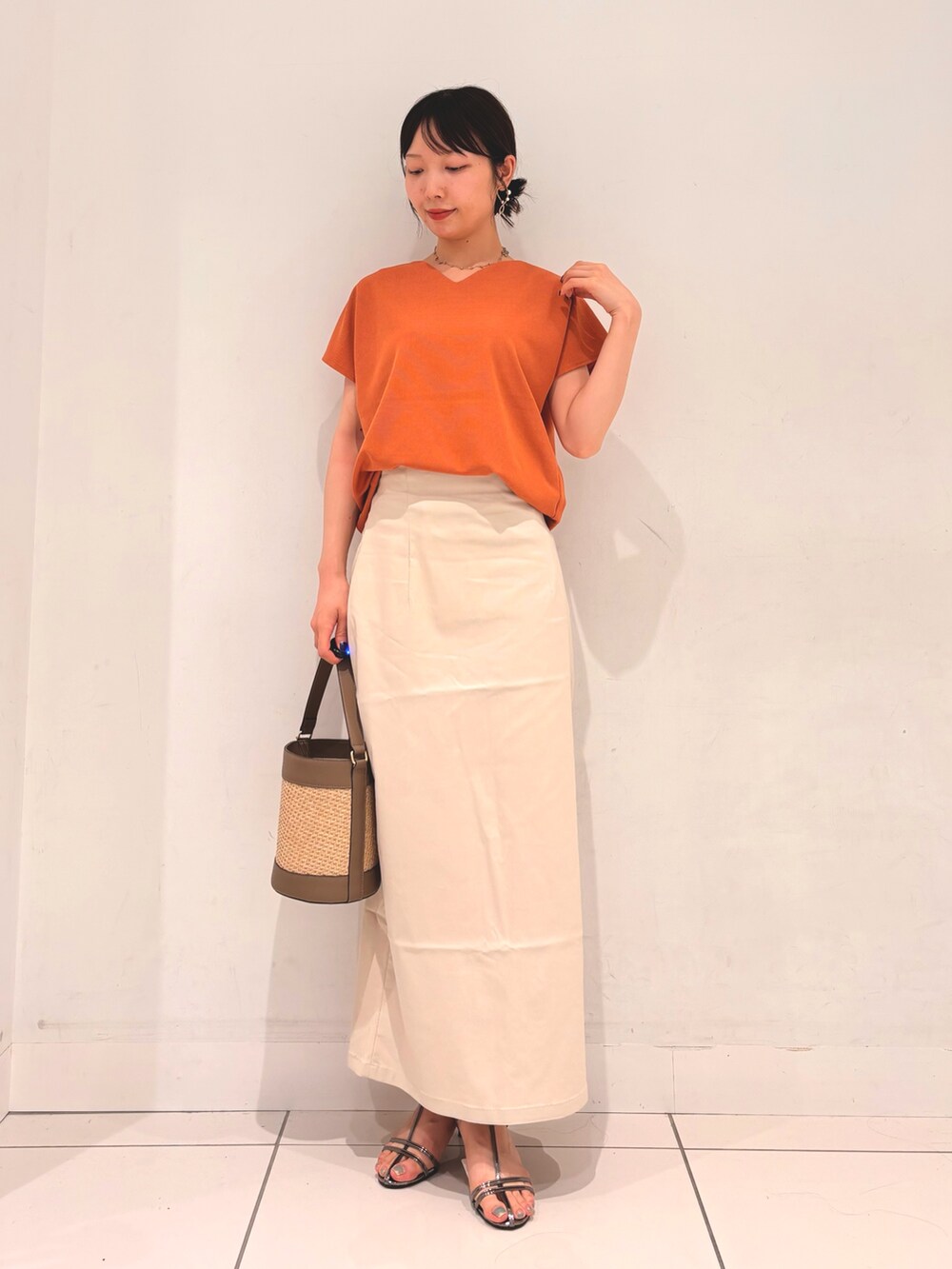 オレンジ系のTシャツ/カットソー、グレー系のショルダーバッグ、ベージュ系のスカートを着用したレディースの夏コーディネートの3枚目の写真
