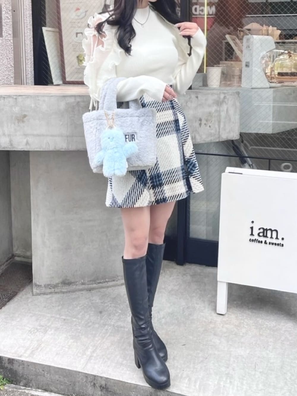 ホワイト系のニット/セーター、ブルー系のトートバッグ、ブラック系のブーツを着用したレディースの秋コーディネートの2枚目の写真