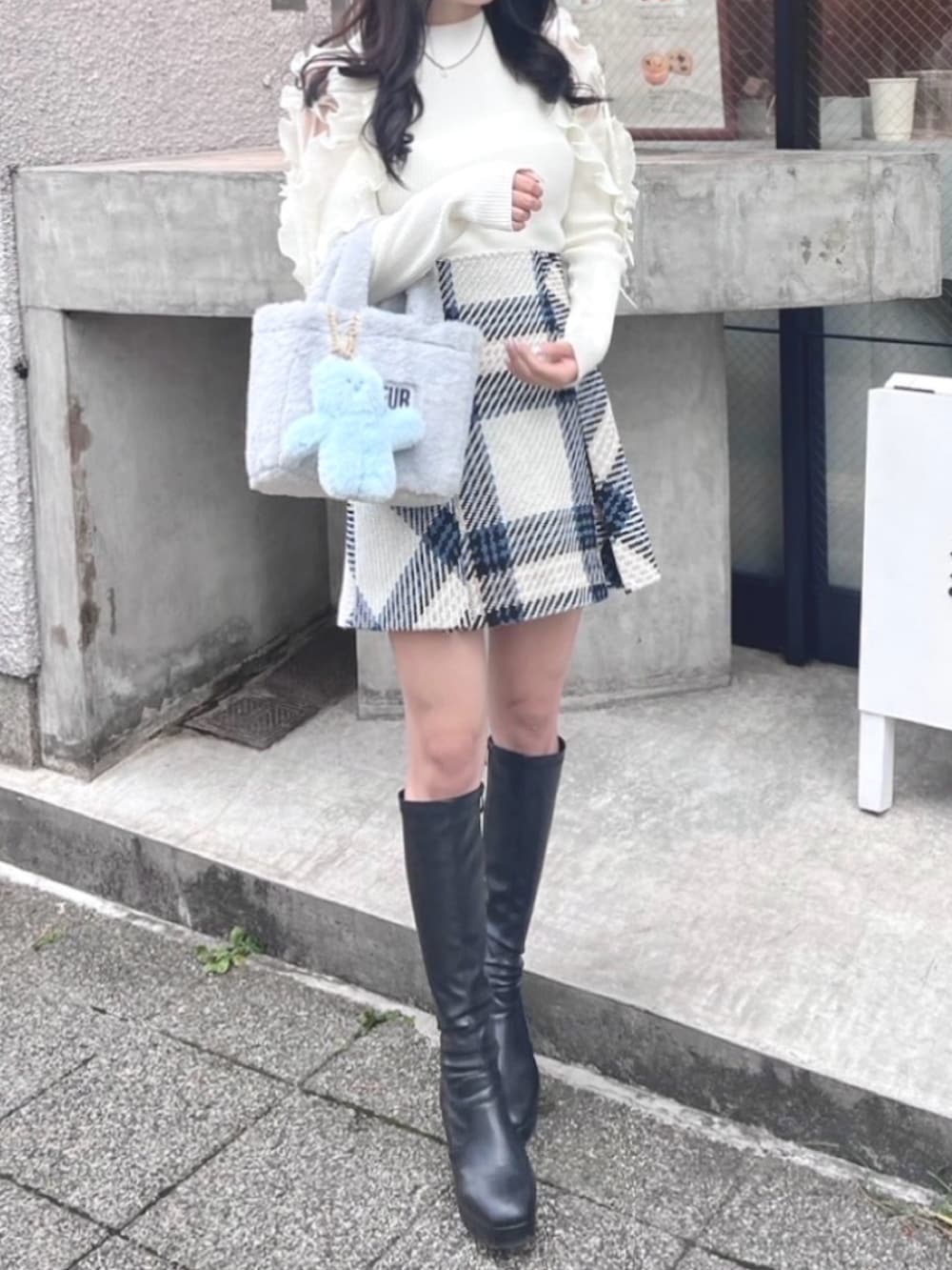 ホワイト系のニット/セーター、ブルー系のトートバッグ、ブラック系のブーツを着用したレディースの秋コーディネートの3枚目の写真