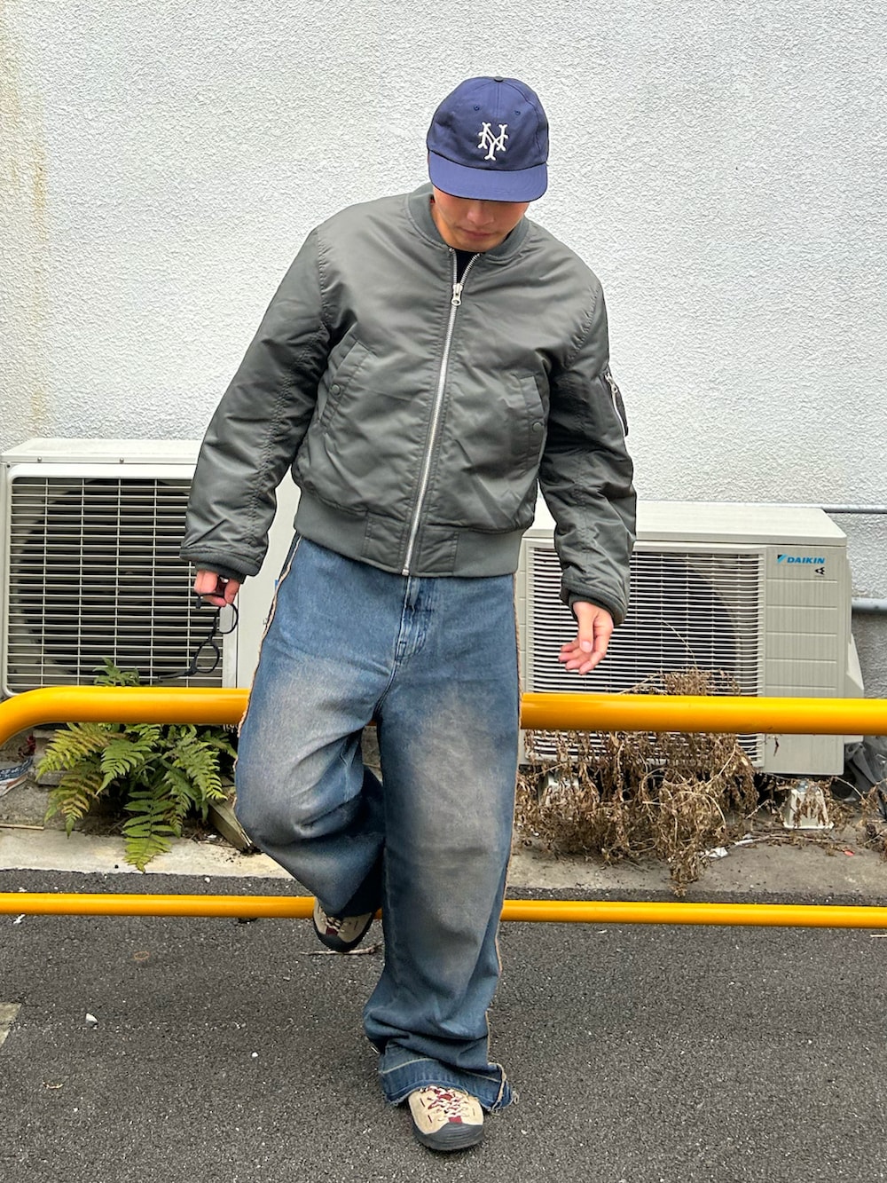 グリーン系のMA-1、ブルー系のデニムパンツ、ベージュ系のスニーカーを着用したメンズの冬コーディネートの2枚目の写真