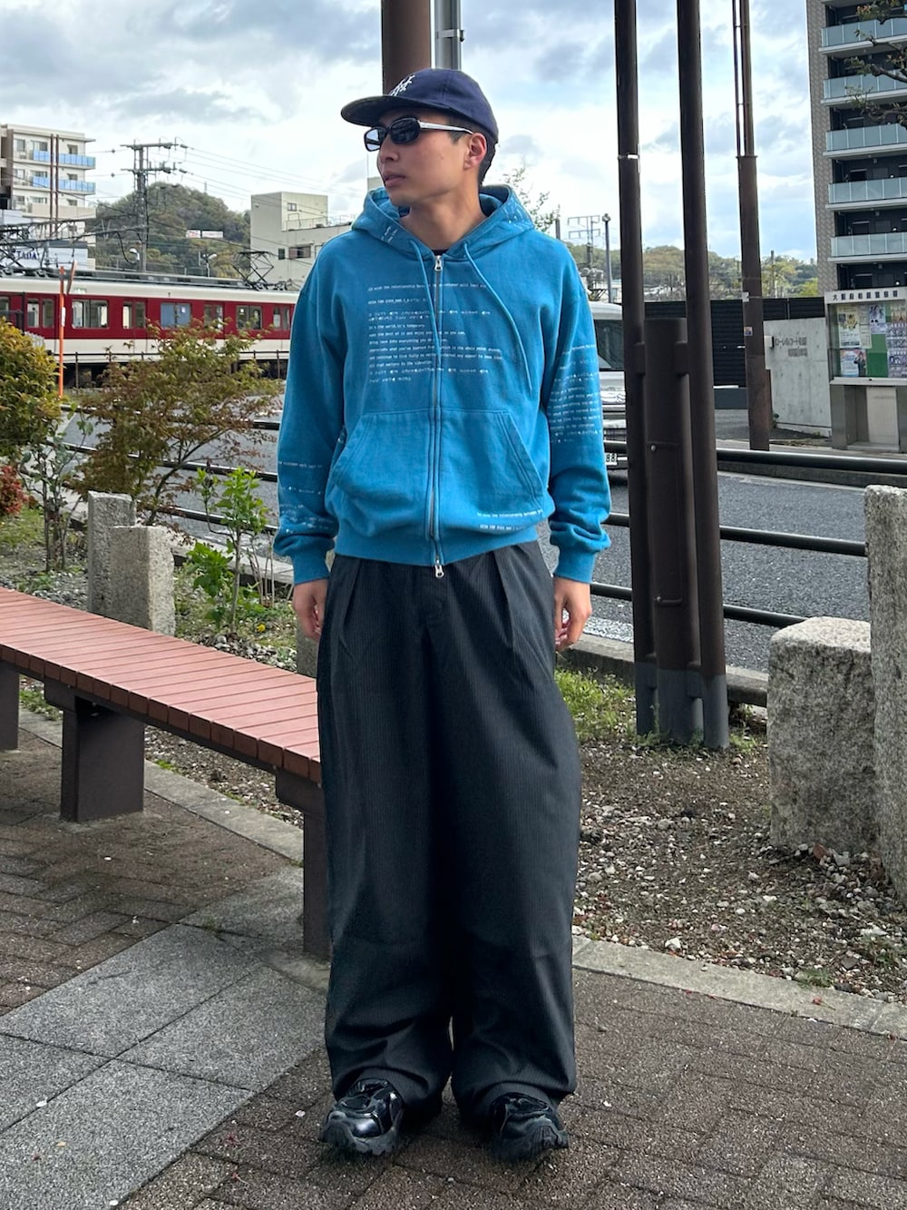 ブルー系のパーカー、グレー系のスラックス、ブラック系のスニーカーを着用したメンズの春コーディネートの2枚目の写真