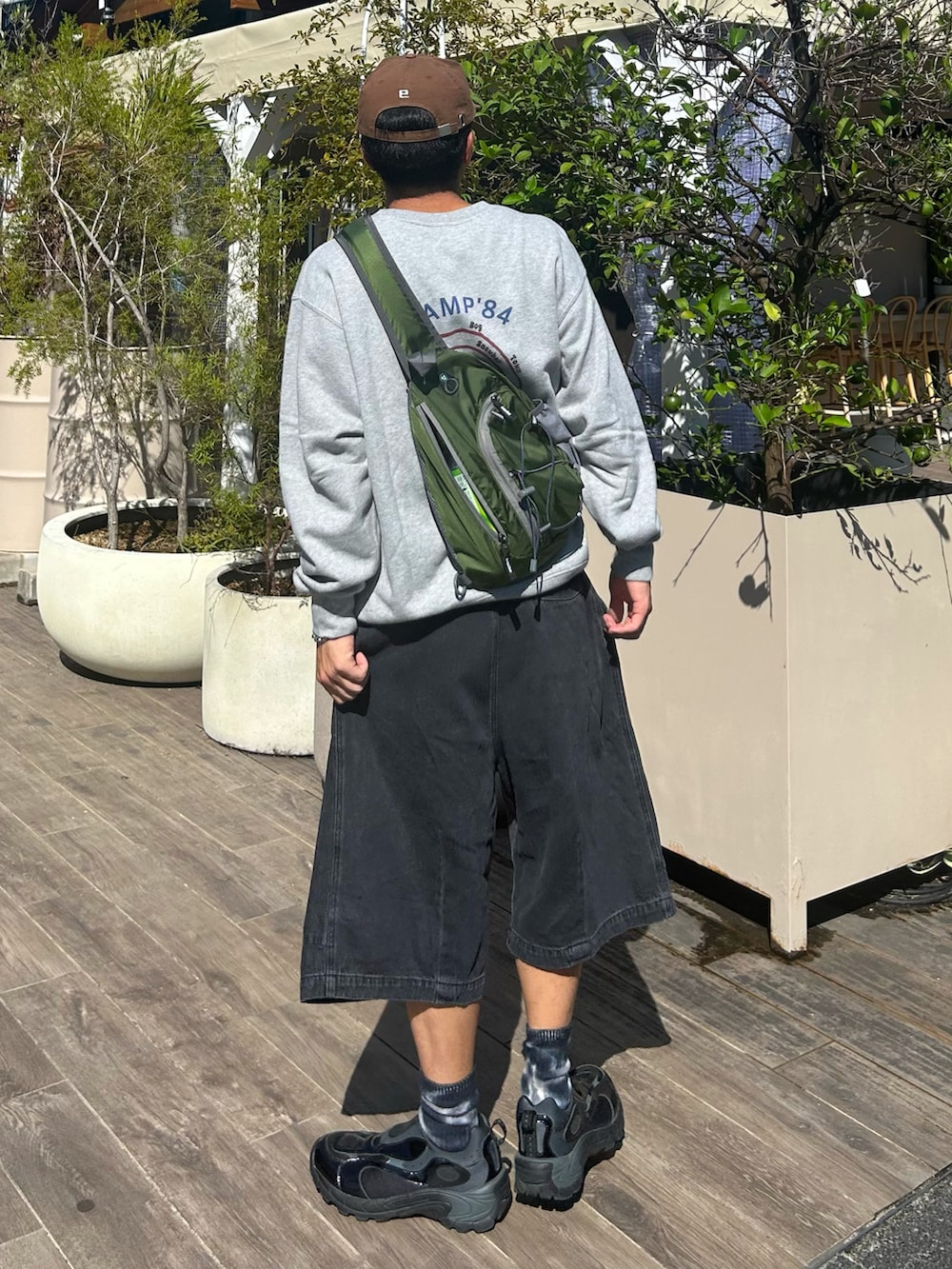 ブラック系のデニムパンツ、グリーン系のショルダーバッグ、グレー系のスウェットを着用したメンズの秋コーディネートの2枚目の写真