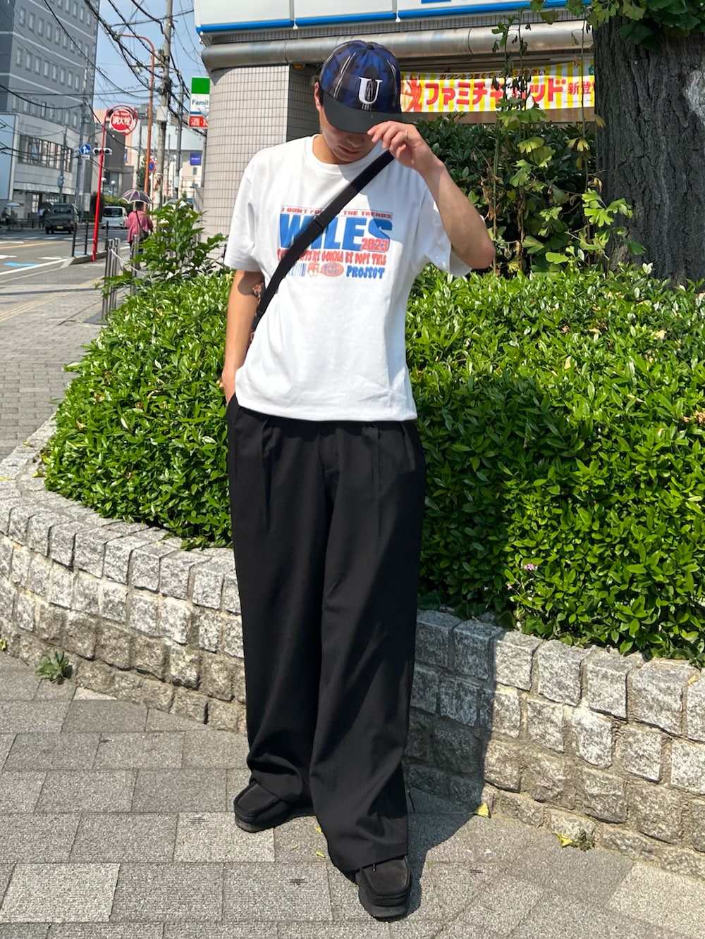 ブラック系のスラックス、ブラック系のブーツ、ホワイト系のTシャツ/カットソーを着用したメンズの夏コーディネートの2枚目の写真