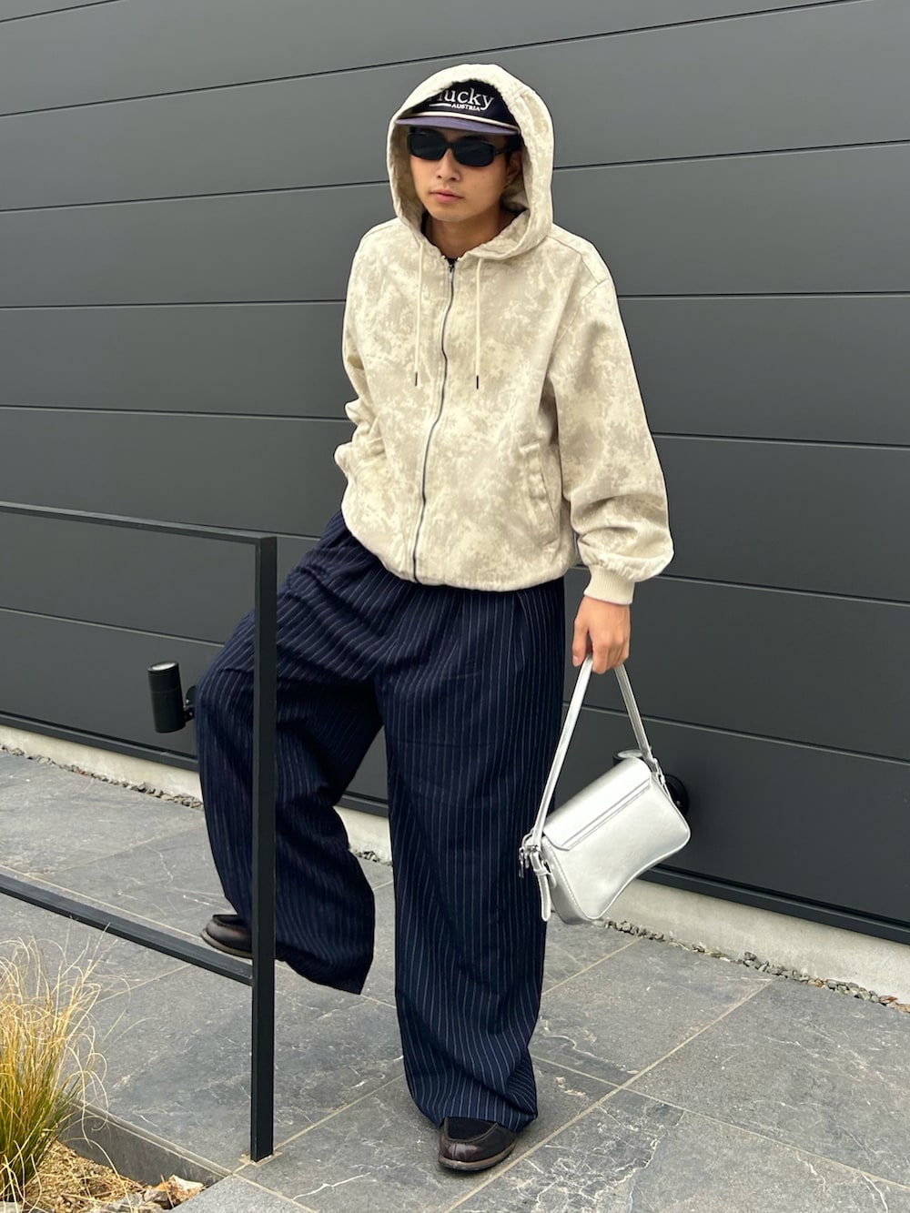 ホワイト系のパーカー、ブルー系のスラックス、シルバー系のショルダーバッグを着用したメンズの春コーディネートの2枚目の写真