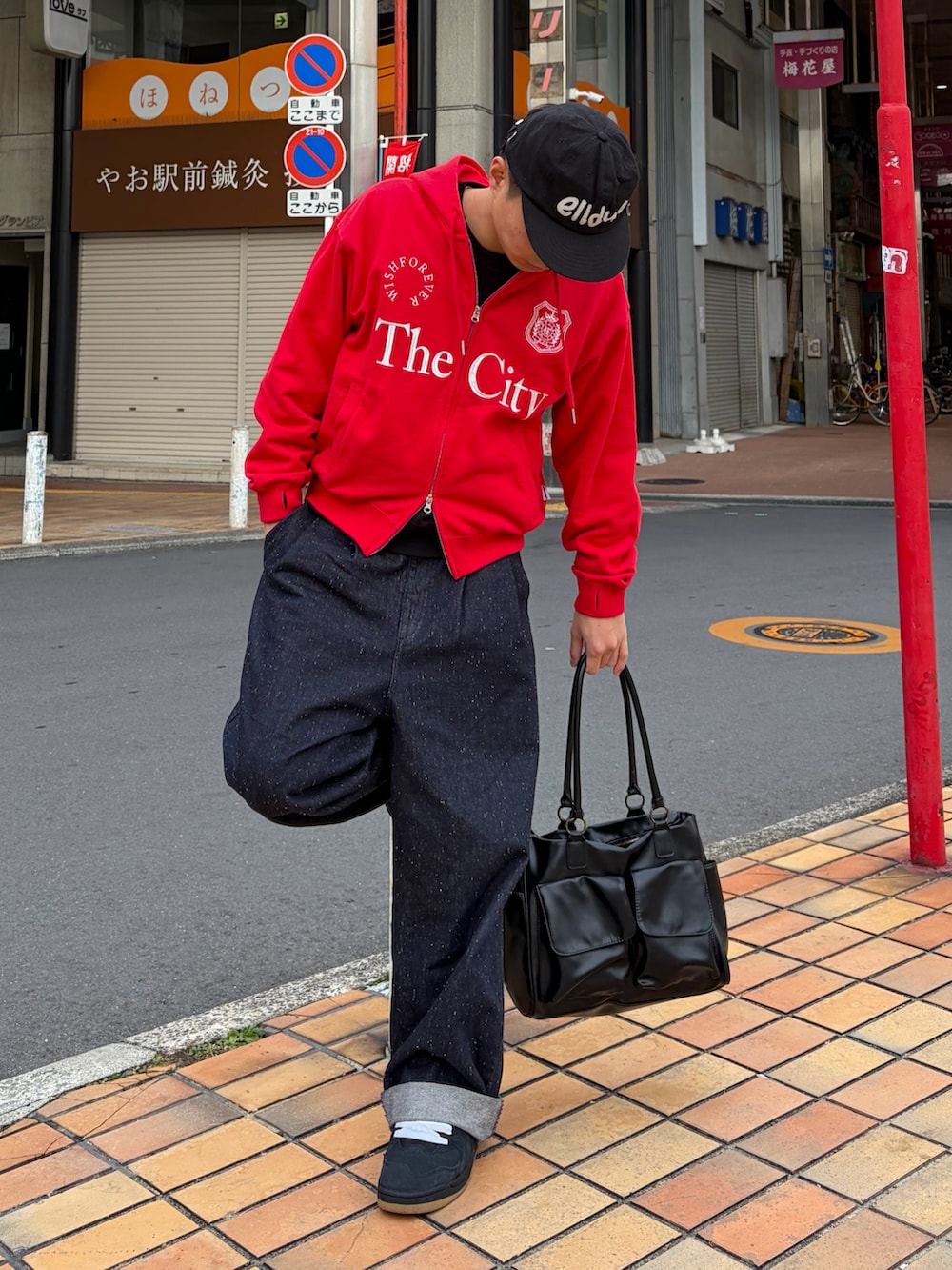 ブルー系のデニムパンツ、ブラック系のボストンバッグ、レッド系のパーカーを着用したメンズの冬コーディネートの2枚目の写真