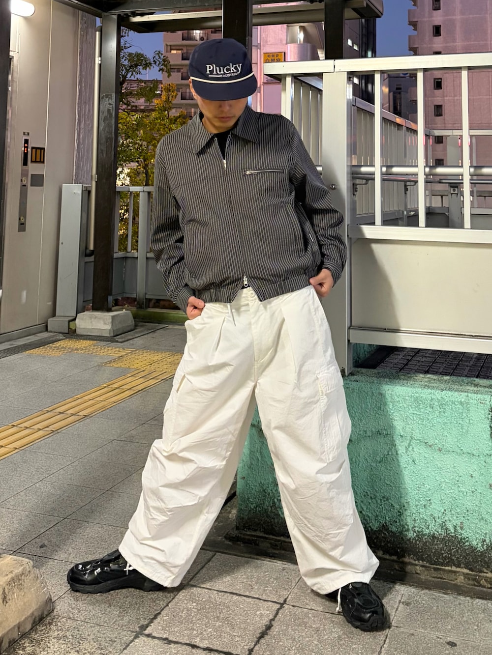 グレー系のブルゾン、ホワイト系のその他パンツ、ブラック系のスニーカーを着用したメンズの冬コーディネートの2枚目の写真