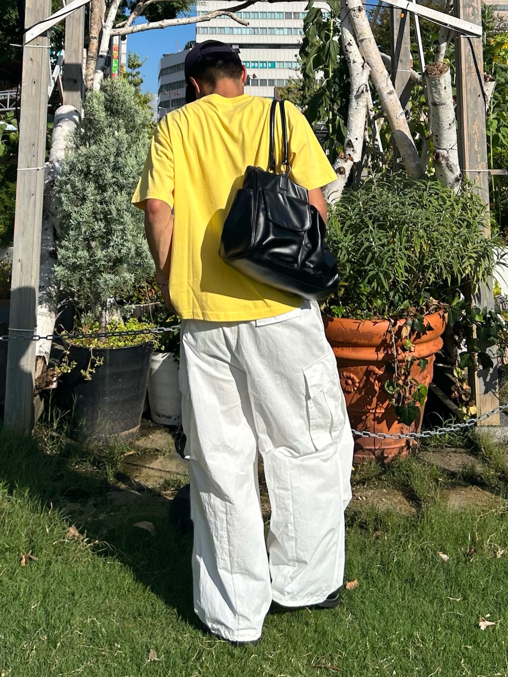 イエロー系のTシャツ/カットソー、ブラック系のボストンバッグ、ブラック系のローファーを着用したメンズの秋コーディネートの2枚目の写真