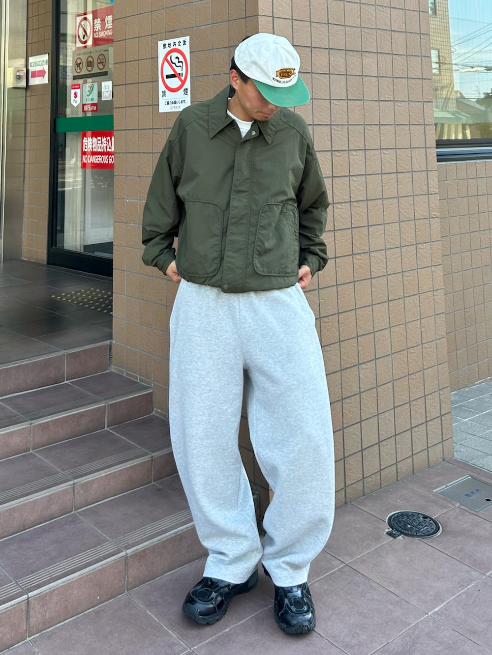 グリーン系のテーラードジャケット、グレー系のスウェットパンツ、ブラック系のスニーカーを着用したメンズの秋コーディネートの2枚目の写真