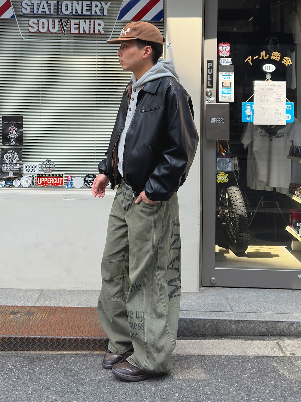 グレー系のパーカー、ブラック系のブルゾン、ブラウン系のスニーカーを着用したメンズの春コーディネートの3枚目の写真
