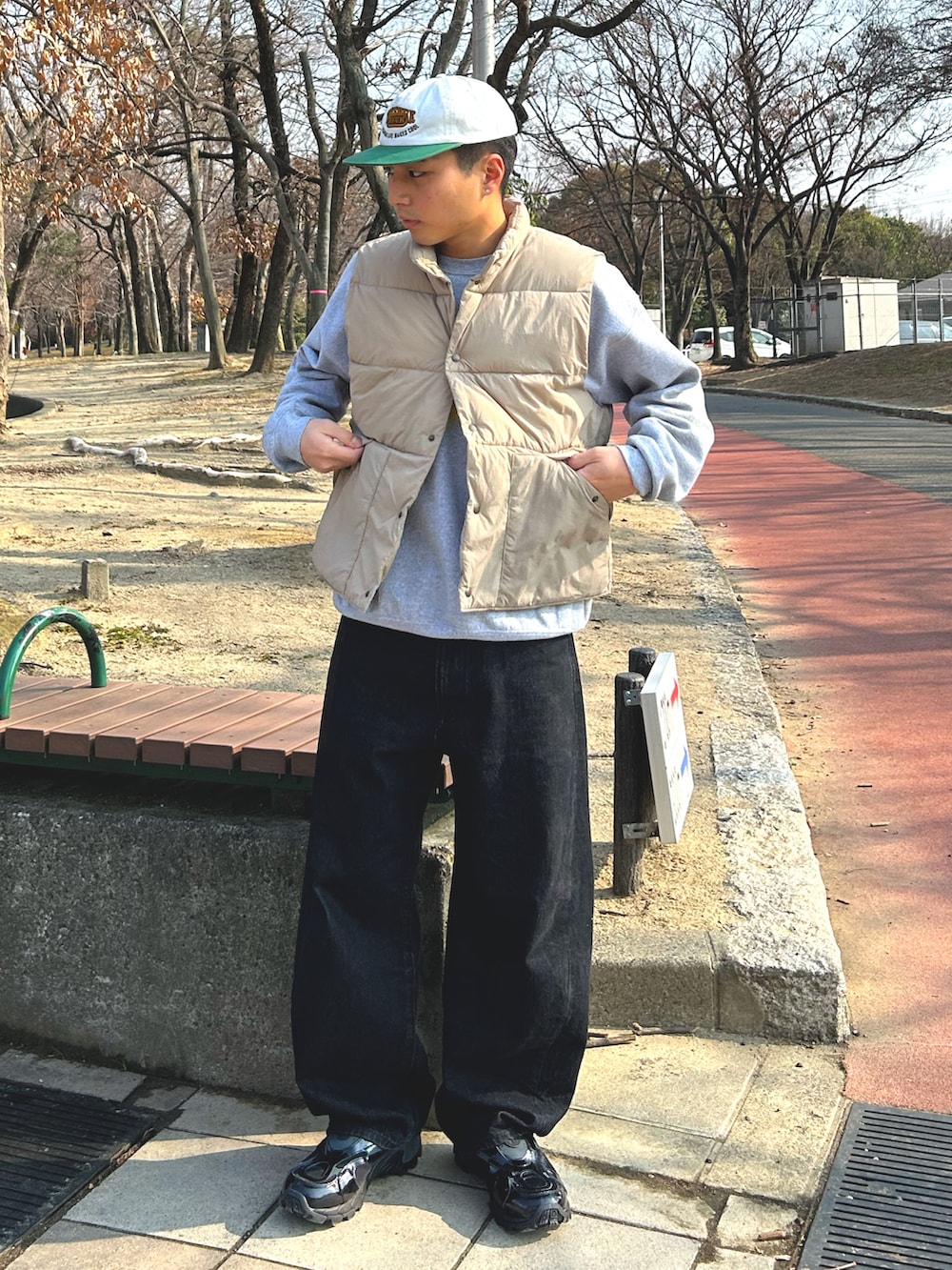 ベージュ系のダウンベスト、ブラック系のデニムパンツ、ブラック系のスニーカーを着用したメンズの冬コーディネートの2枚目の写真