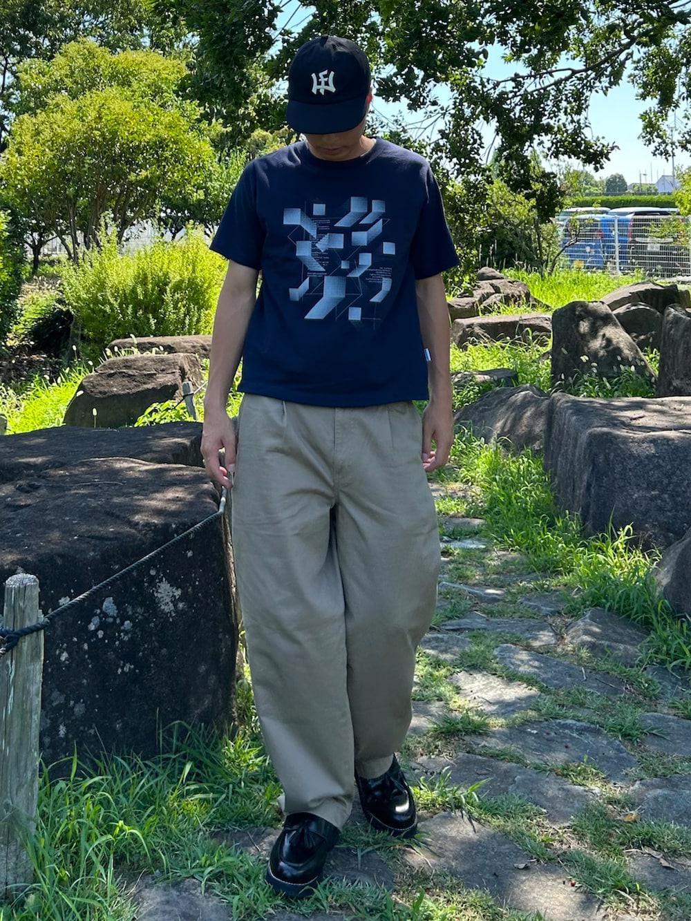 ブルー系のTシャツ/カットソー、ブラック系のローファー、ベージュ系のデニムパンツを着用したメンズの夏コーディネートの2枚目の写真