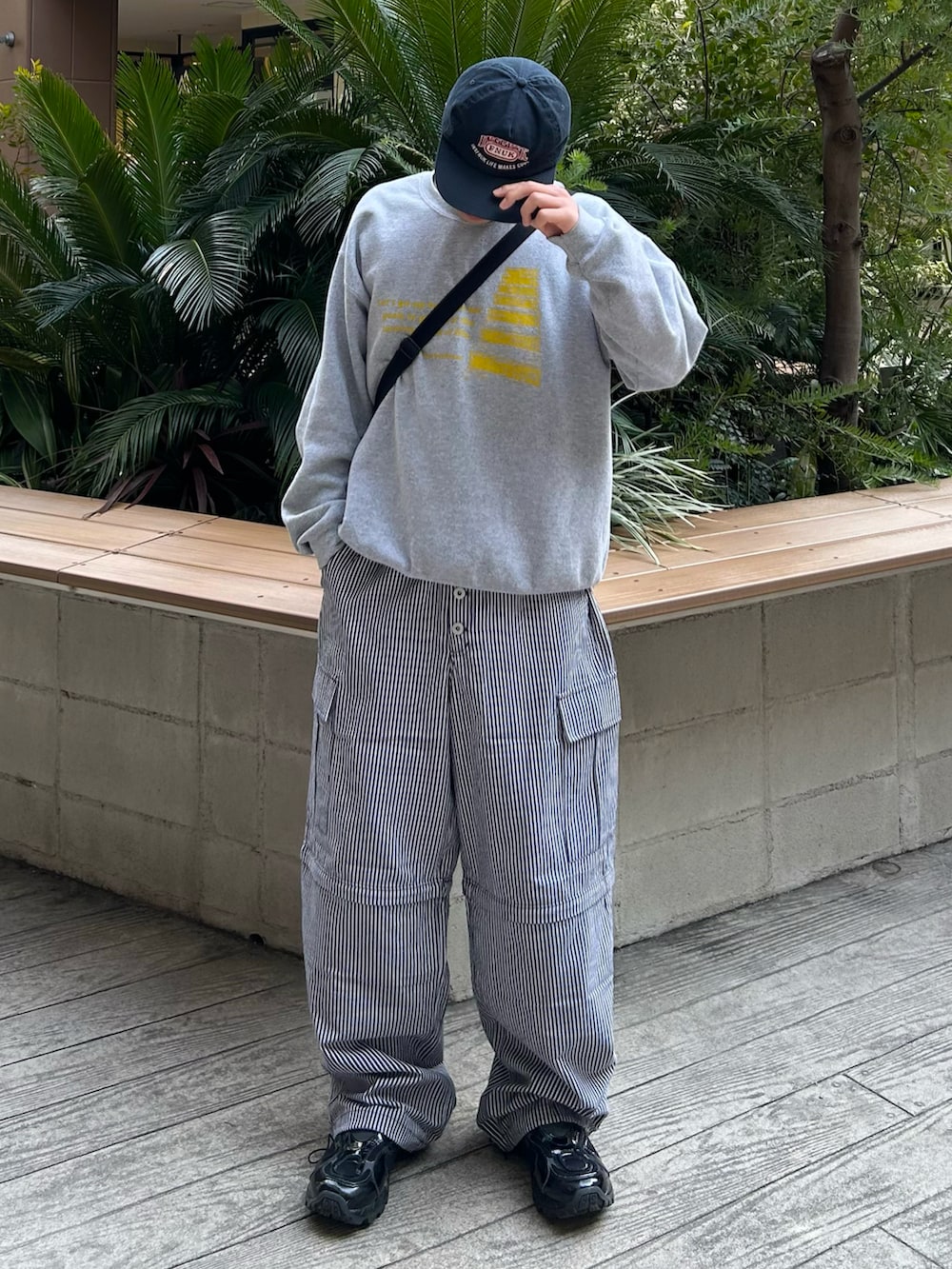 グレー系のスウェット、ブラック系のカーゴパンツ、ブラック系のスニーカーを着用したメンズの春コーディネートの2枚目の写真