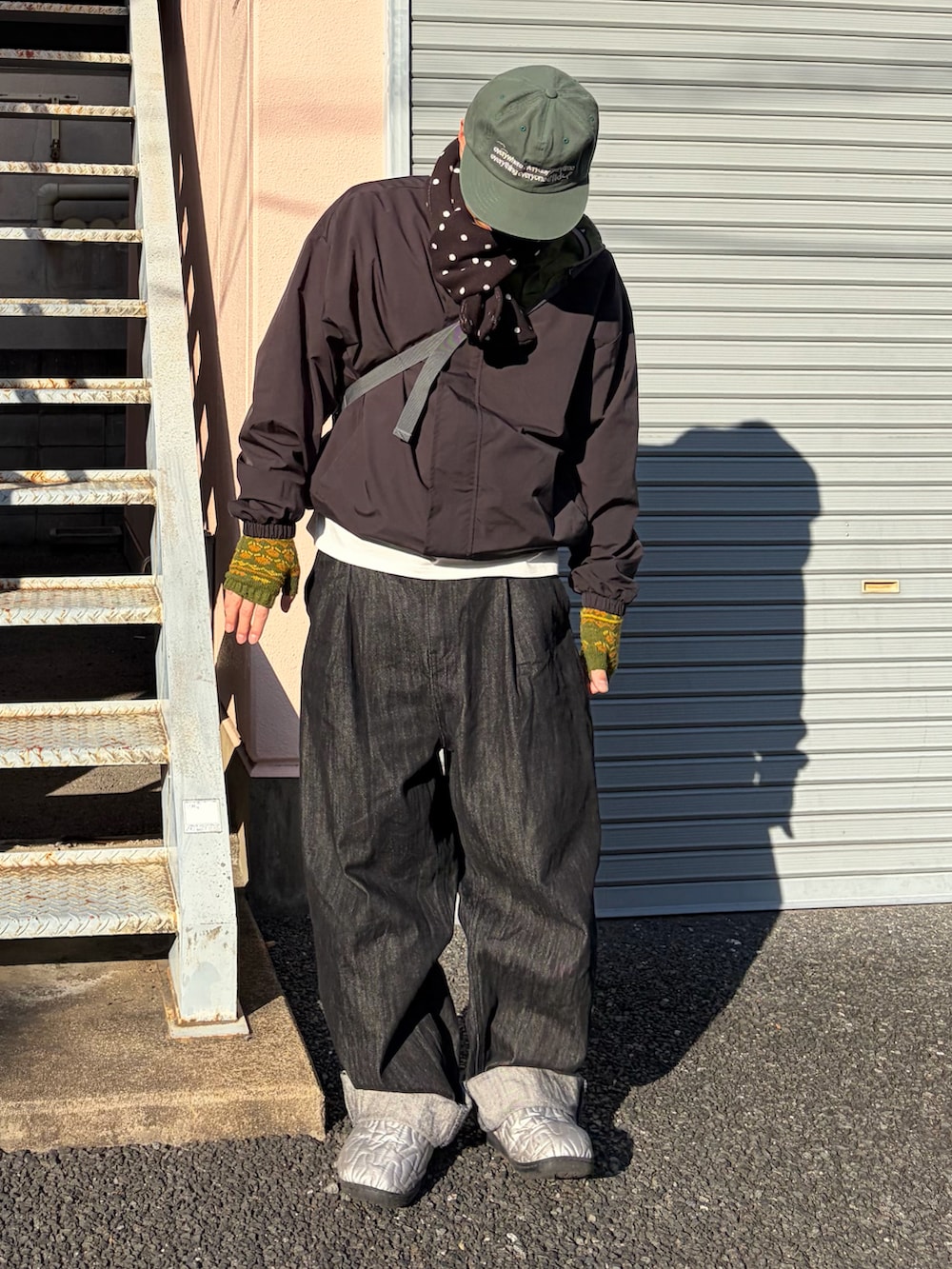 シルバー系のサンダル、ブラック系のナイロンジャケット、ブラック系のデニムパンツを着用したメンズの冬コーディネートの2枚目の写真