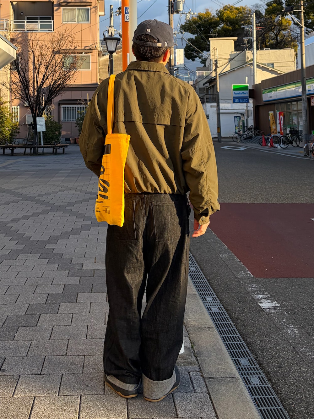 グリーン系のテーラードジャケット、ブラック系のデニムパンツ、イエロー系のトートバッグを着用したメンズの冬コーディネートの2枚目の写真