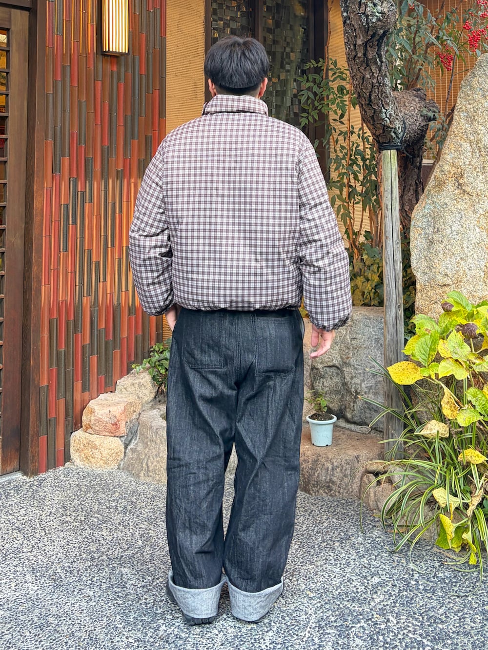 ブラウン系のダウンジャケット/コート、ブラック系のデニムパンツ、ブラック系のスニーカーを着用したメンズの冬コーディネートの2枚目の写真